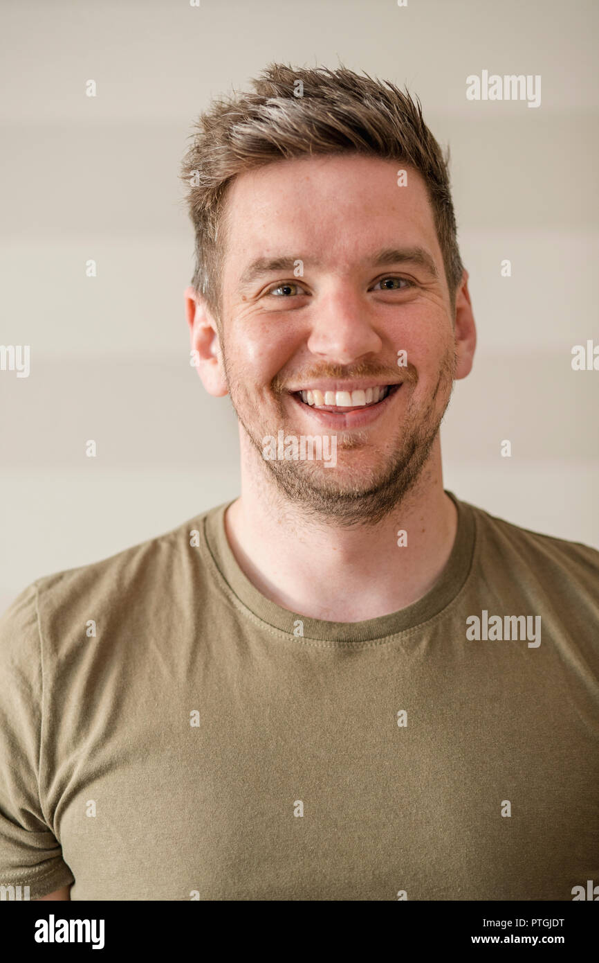 Mid-adult man in a green t-shirt smiling while looking at the camera for a portrait. Stock Photo