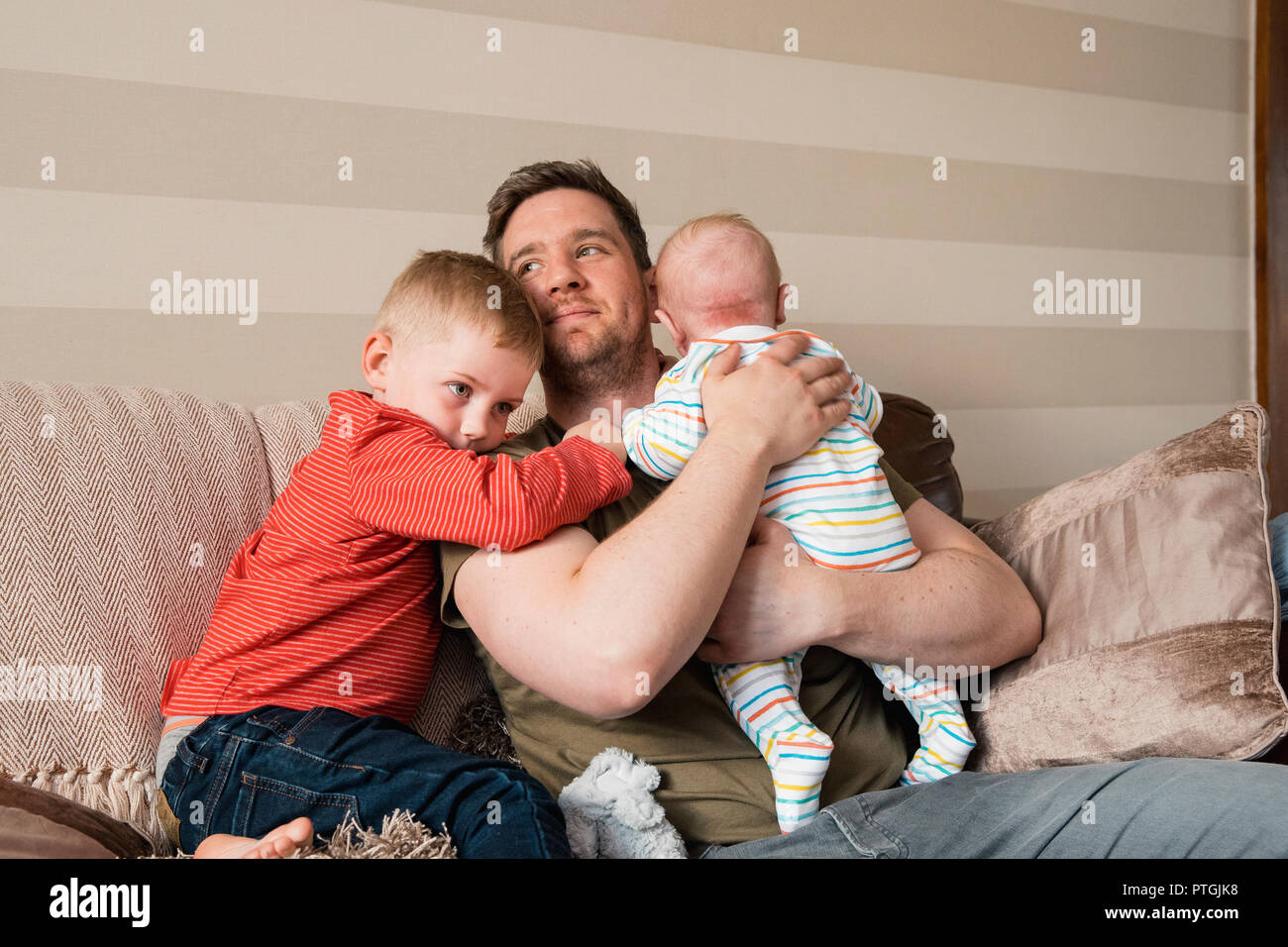 Father and his two sons sitting on the sofa and relaxing. The little