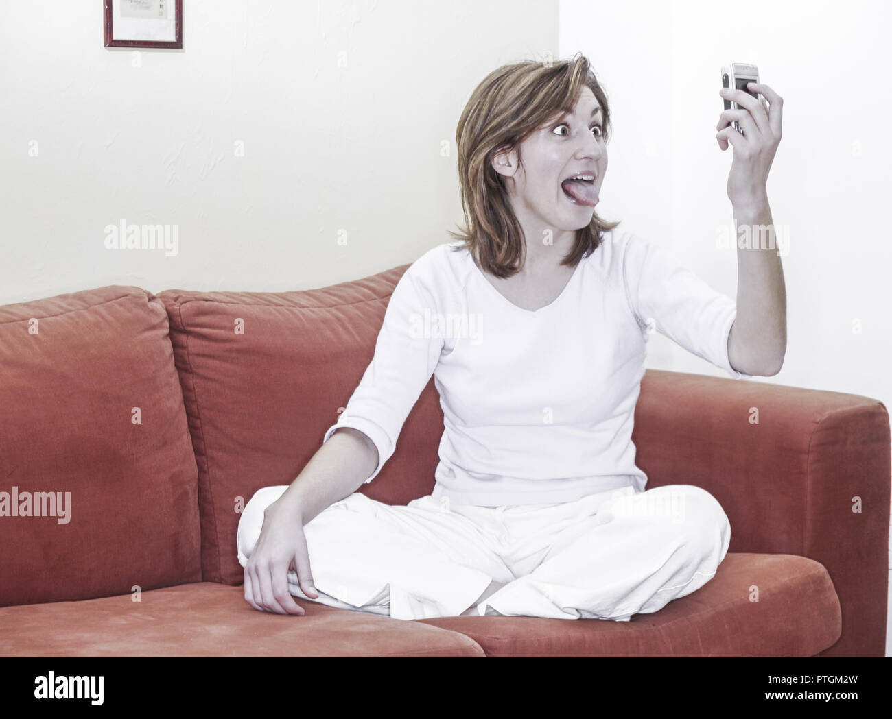 Young Woman Twen Sitting Cross Legged On A Red Couch Taking A Picture Young Woman Twen Sitting Cross Legged On A Red Couch Taking A Picture