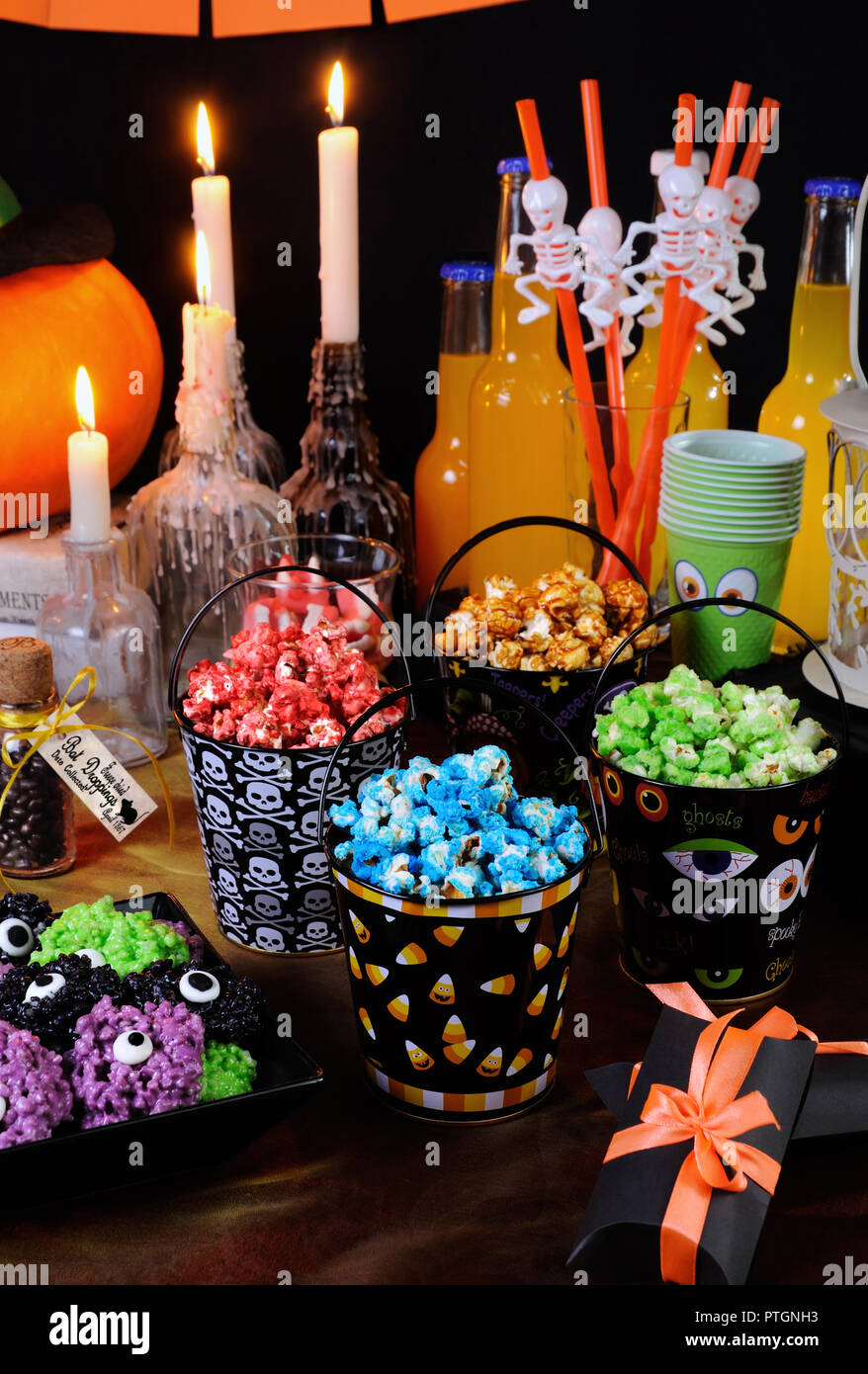 Sweet colored popcorn on the table among Halloween sweetness. Stock Photo