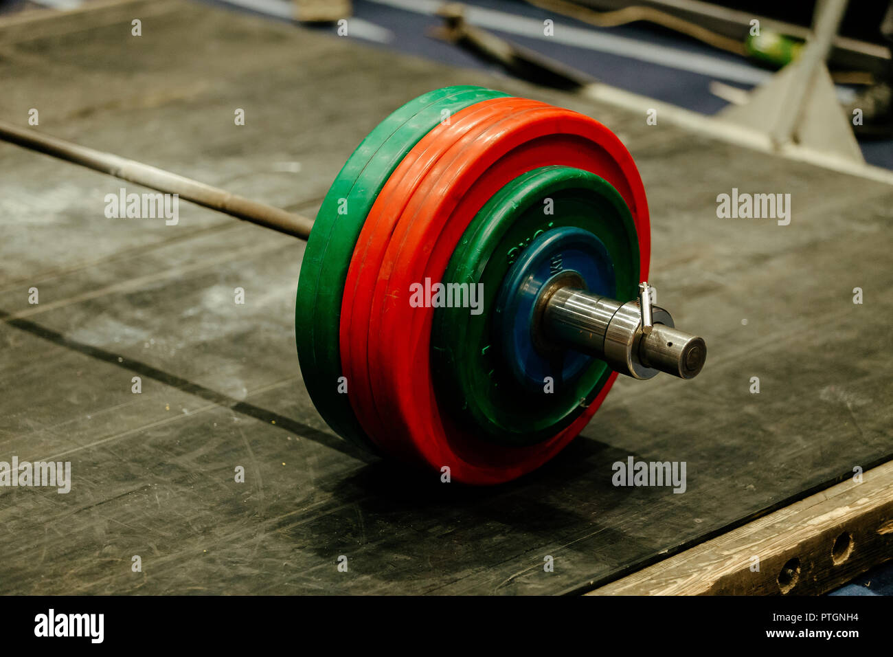 barbell with green and red plates on platform for powerlifting Stock