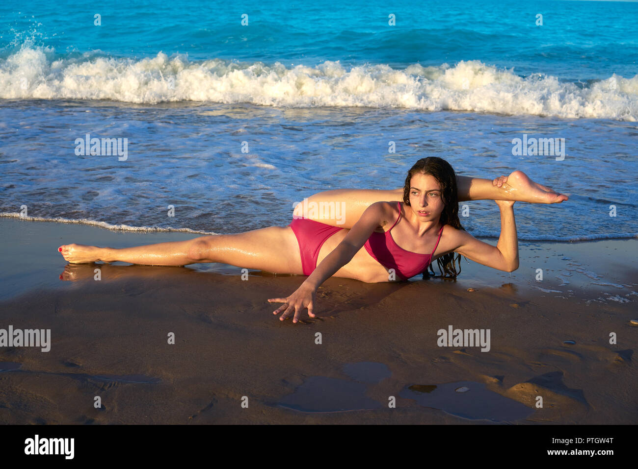 acrobatic gymnastics bikini girl in a beach blue shore at summer Stock