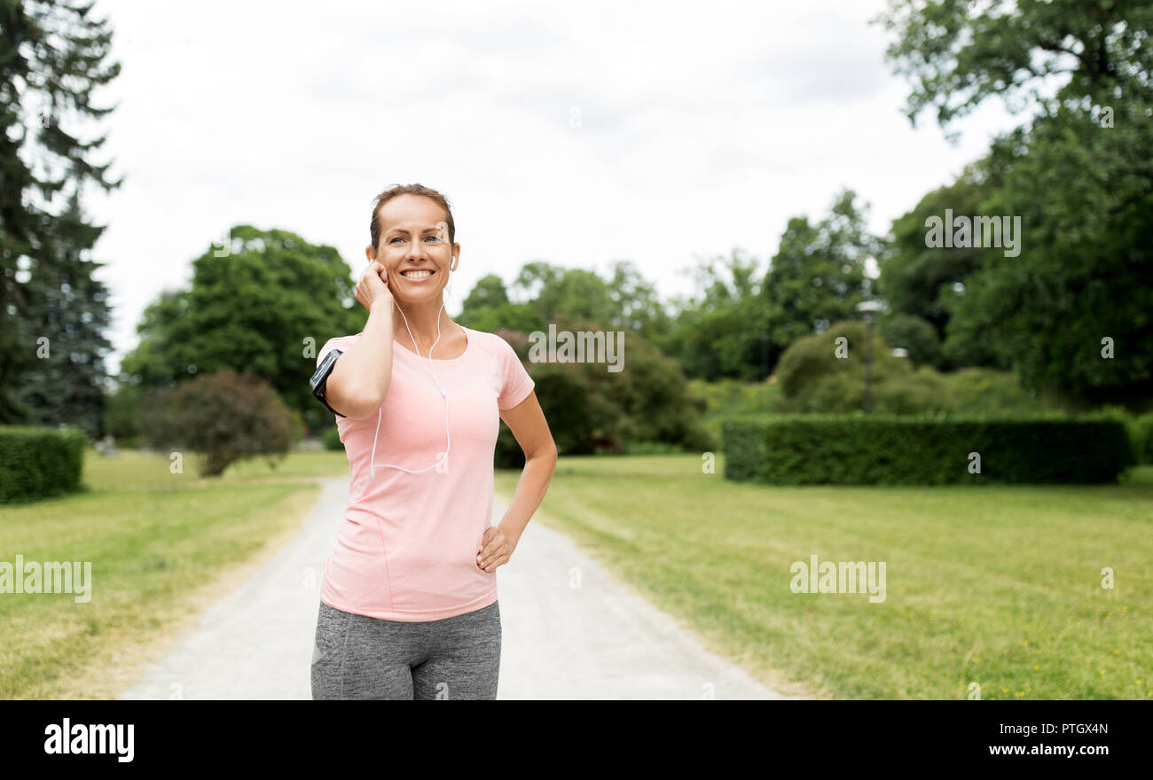 woman with earphones and armband at park Stock Photo