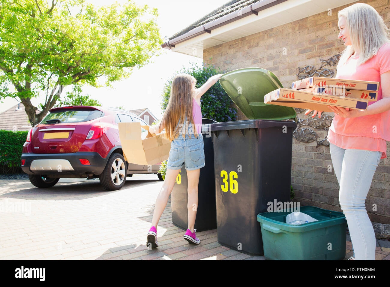 Mother and daughter recycling cardboard in driveway Stock Photo