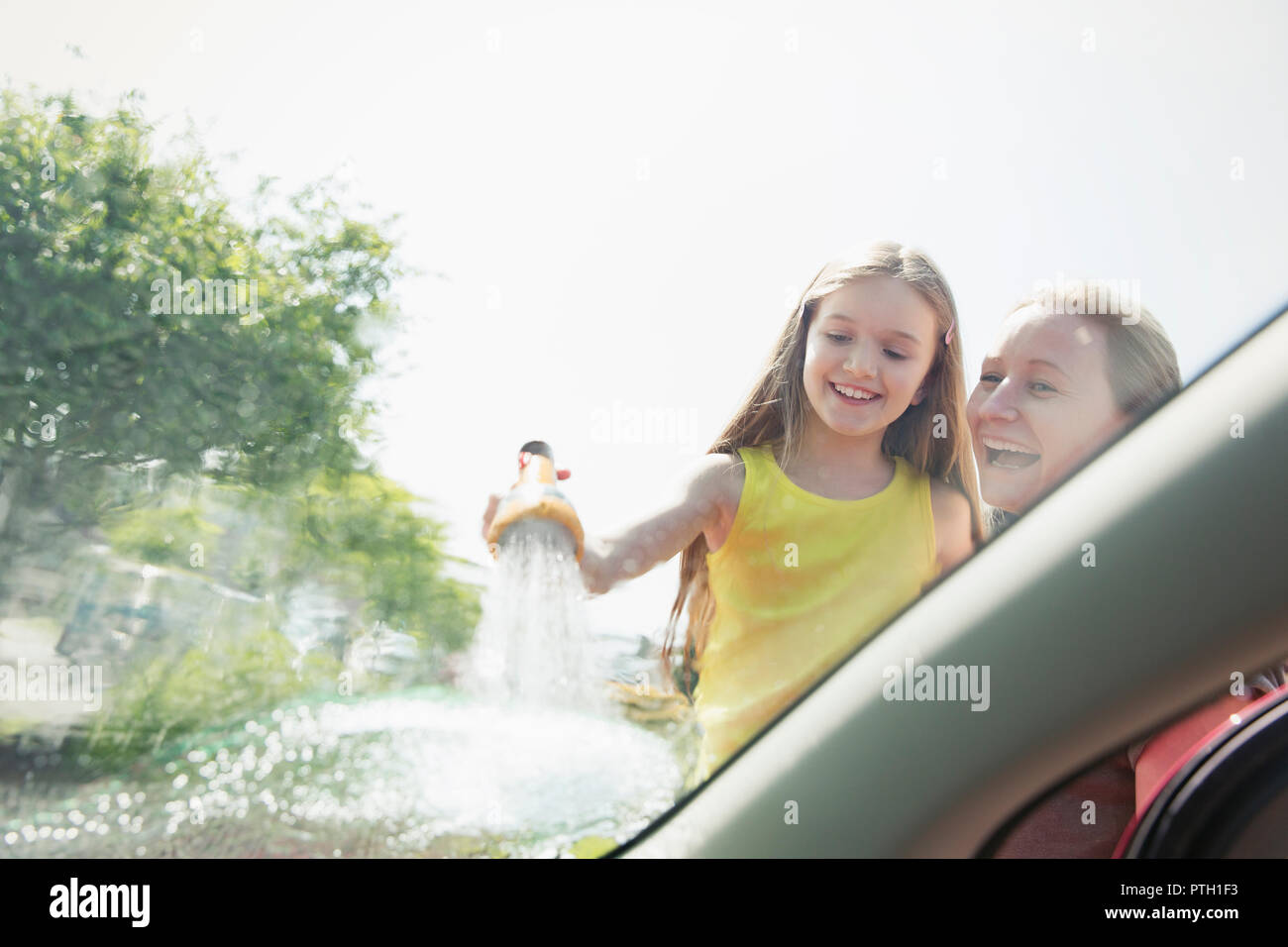 Mother and daughter washing car windshield Stock Photo