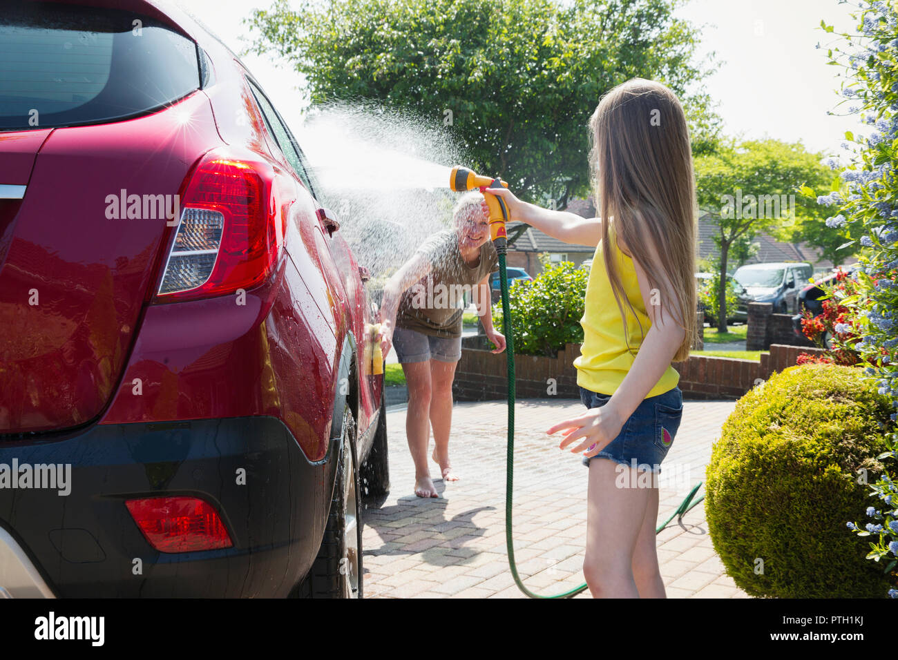 Mother and daughter washing car in sunny driveway Stock Photo Alamy