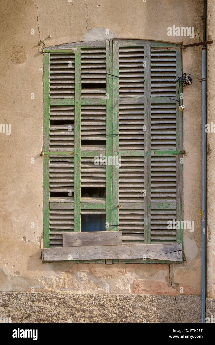 Repaired but delapidated and weather worn green shutter on an old building in Alcudia, Mallorca, Spain Stock Photo