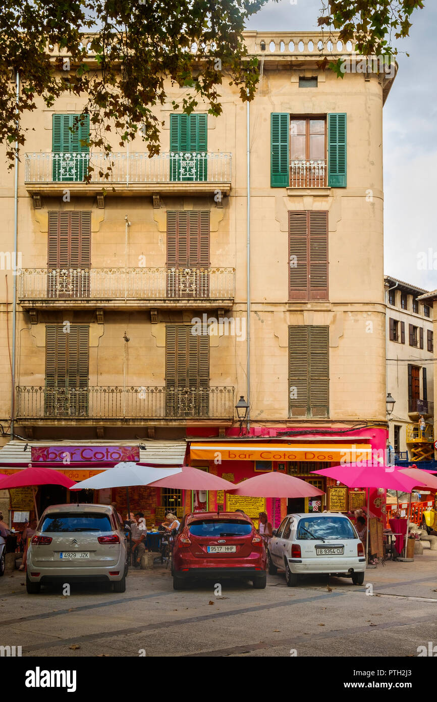 Bright pinks of parasols and bar, cafe signs on a corner of the old town, Palma, Mallorca, Spain Stock Photo