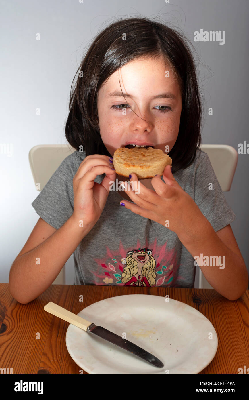 Young girl eating a toasted crumpet for breakfast Stock Photo