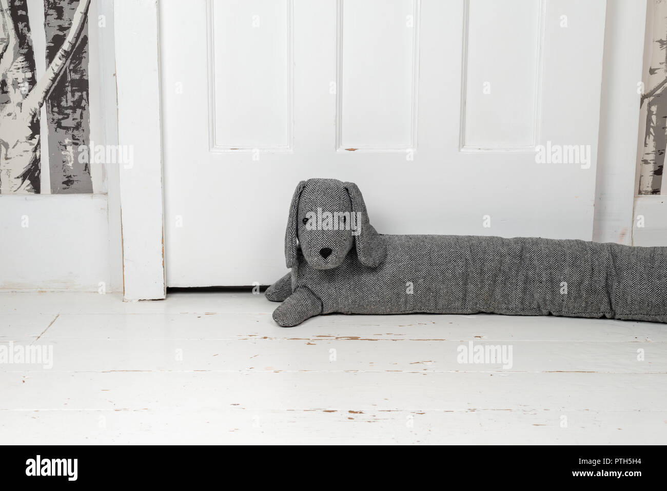 Dog shaped draught excluder on a white painted wooden floor and in