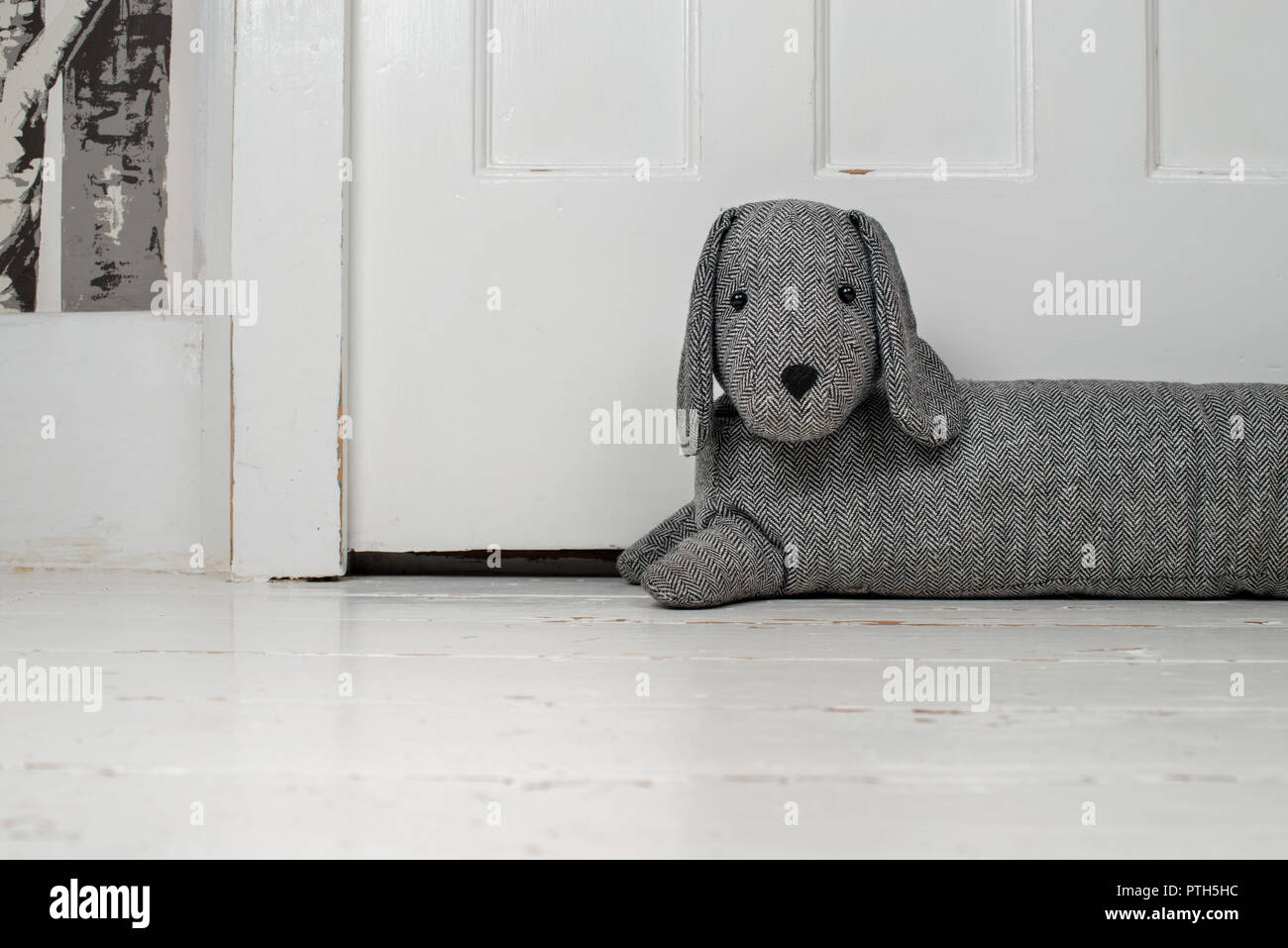 Dog shaped draught excluder on a white painted wooden floor and in
