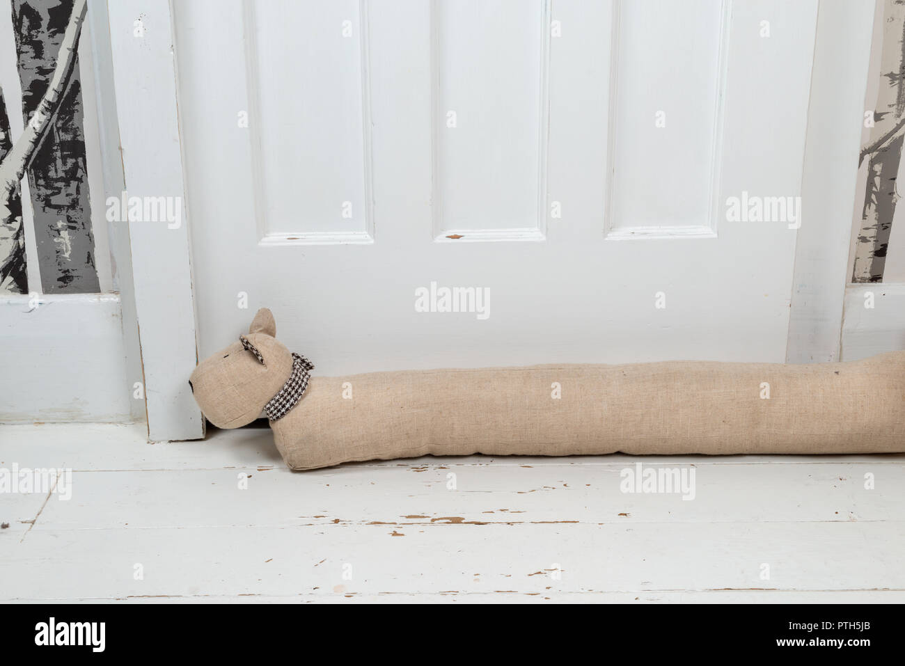 Dog shaped draught excluder on a white painted wooden floor and in