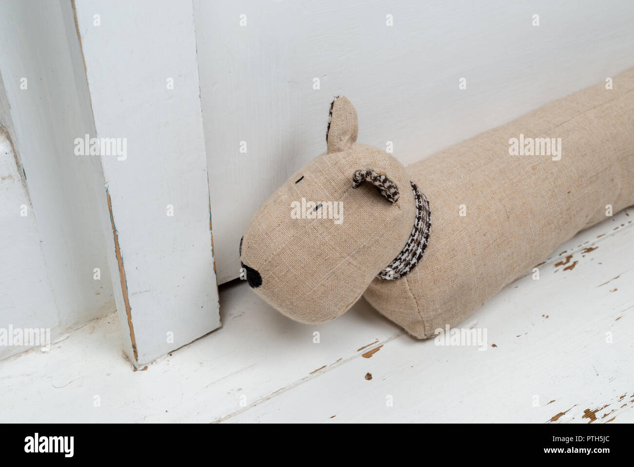 Dog shaped draught excluder on a white painted wooden floor and in