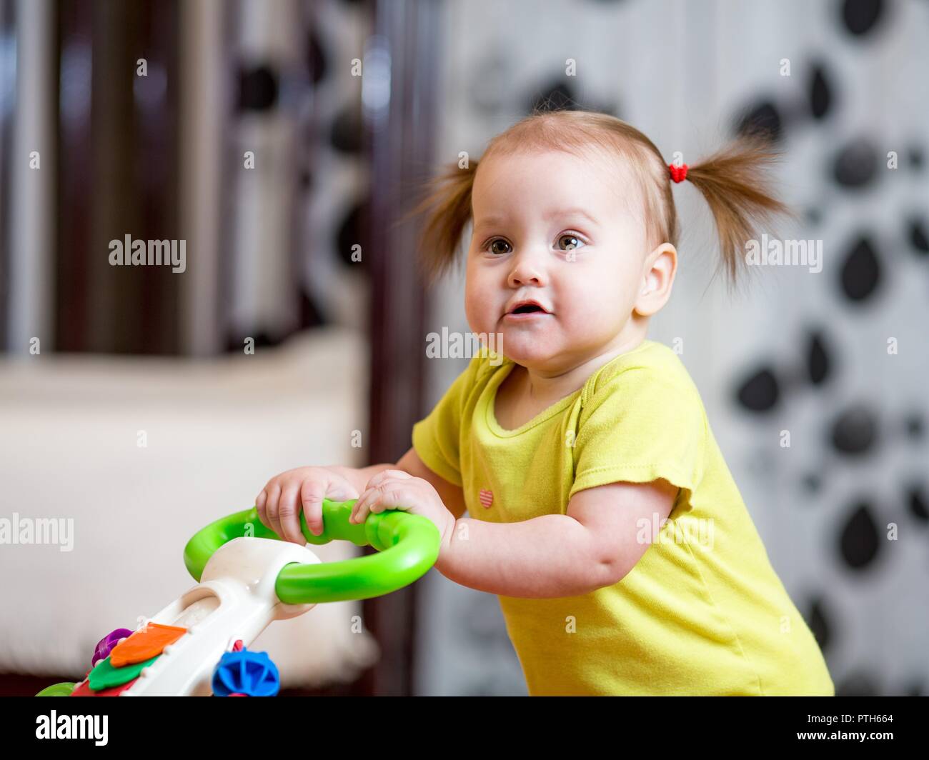 First steps of little kid girl in baby walker Stock Photo - Alamy