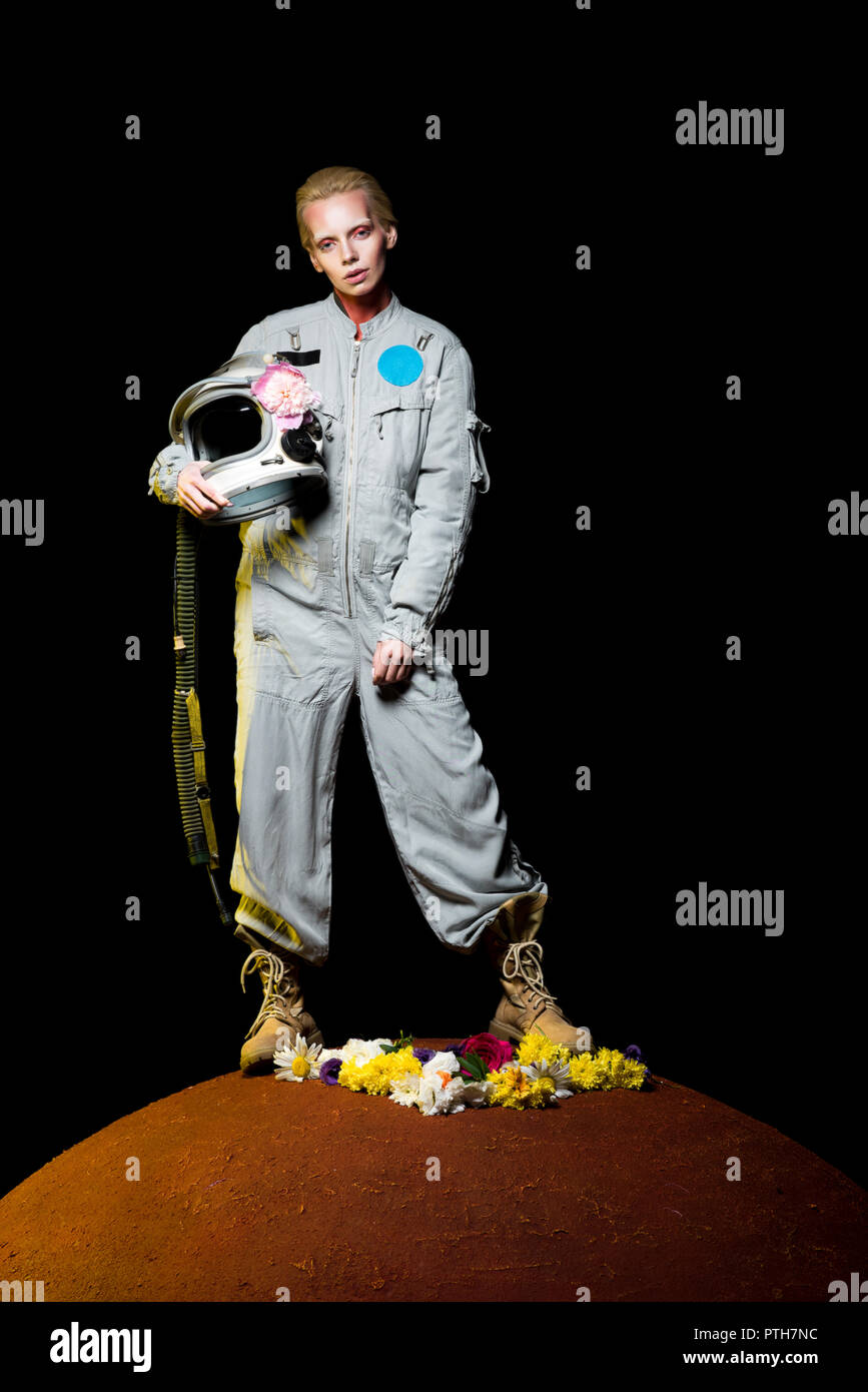 beautiful female cosmonaut posing in spacesuit with flowers and helmet on mars Stock Photo