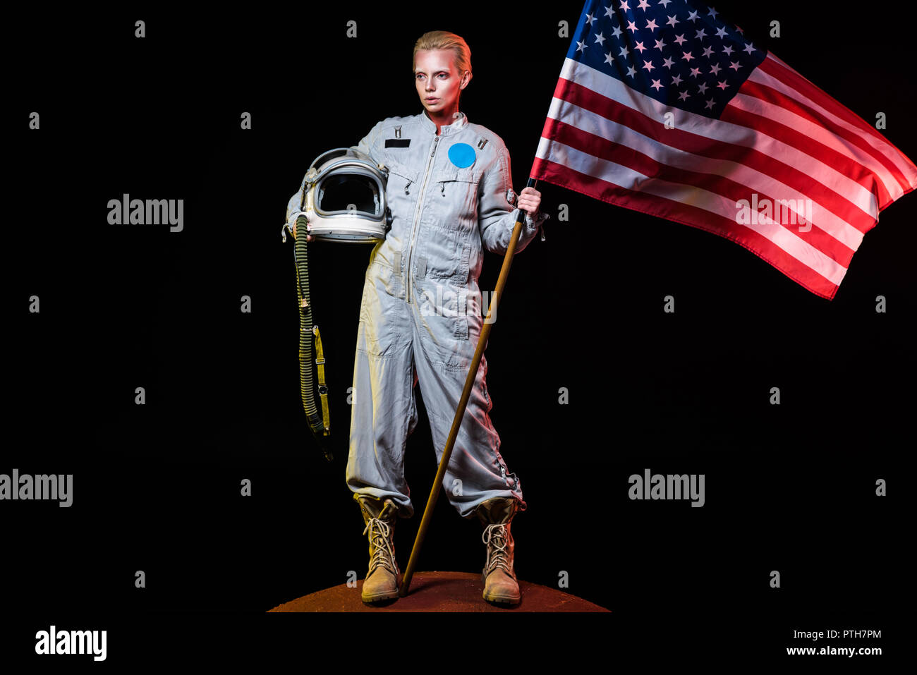 spacewoman in spacesuit holding helmet and american flag on mars Stock Photo