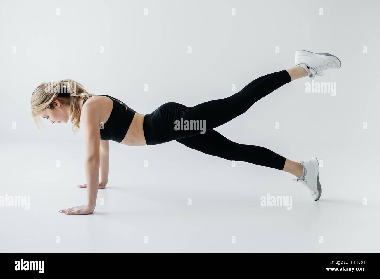 side view of young sportswoman doing push ups isolated on grey Stock ...