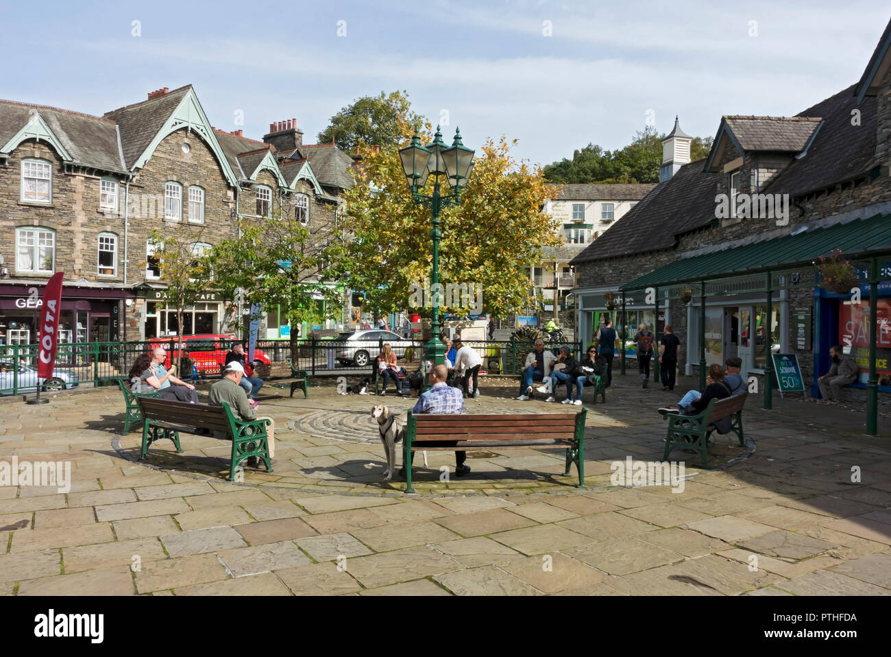 People tourists visitors relaxing sitting outside in the town centre in summer Ambleside Cumbria England UK United Kingdom GB Great Britain Stock Photo