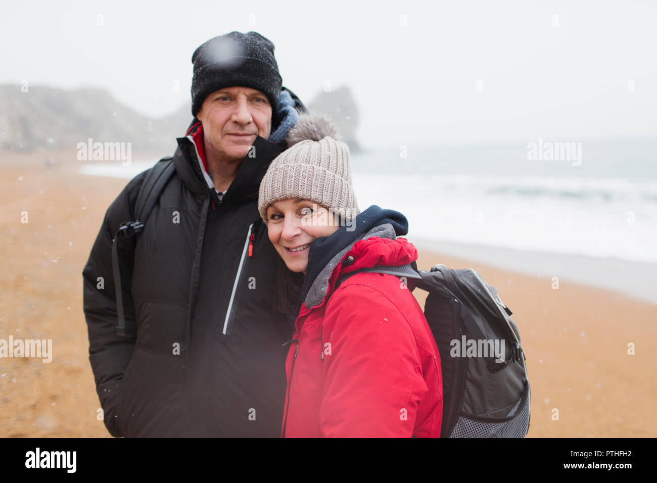 Portrait couple in warm clothing on winter beach Stock Photo