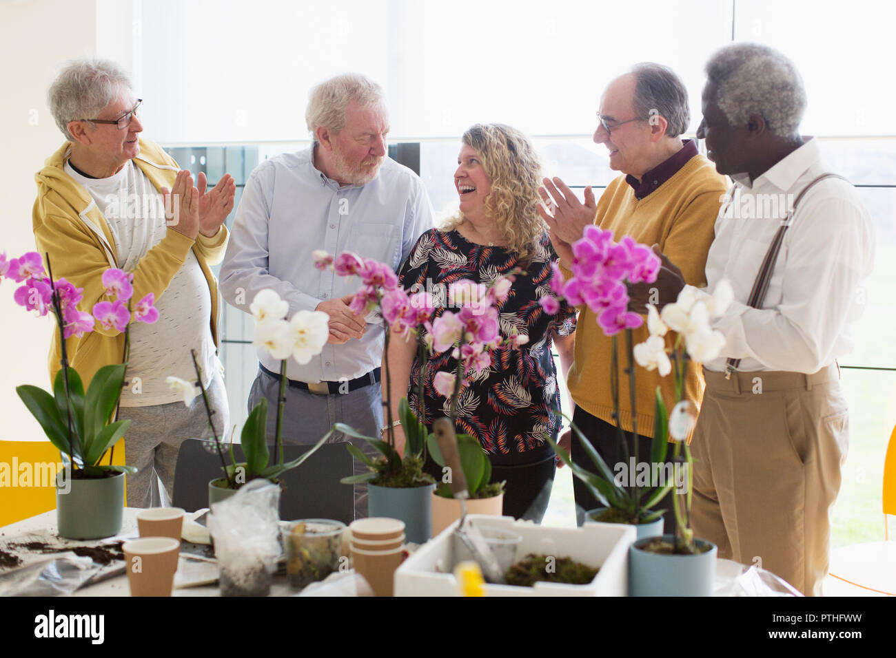 Active senior men clapping for female instructor in flower arranging class Stock Photo