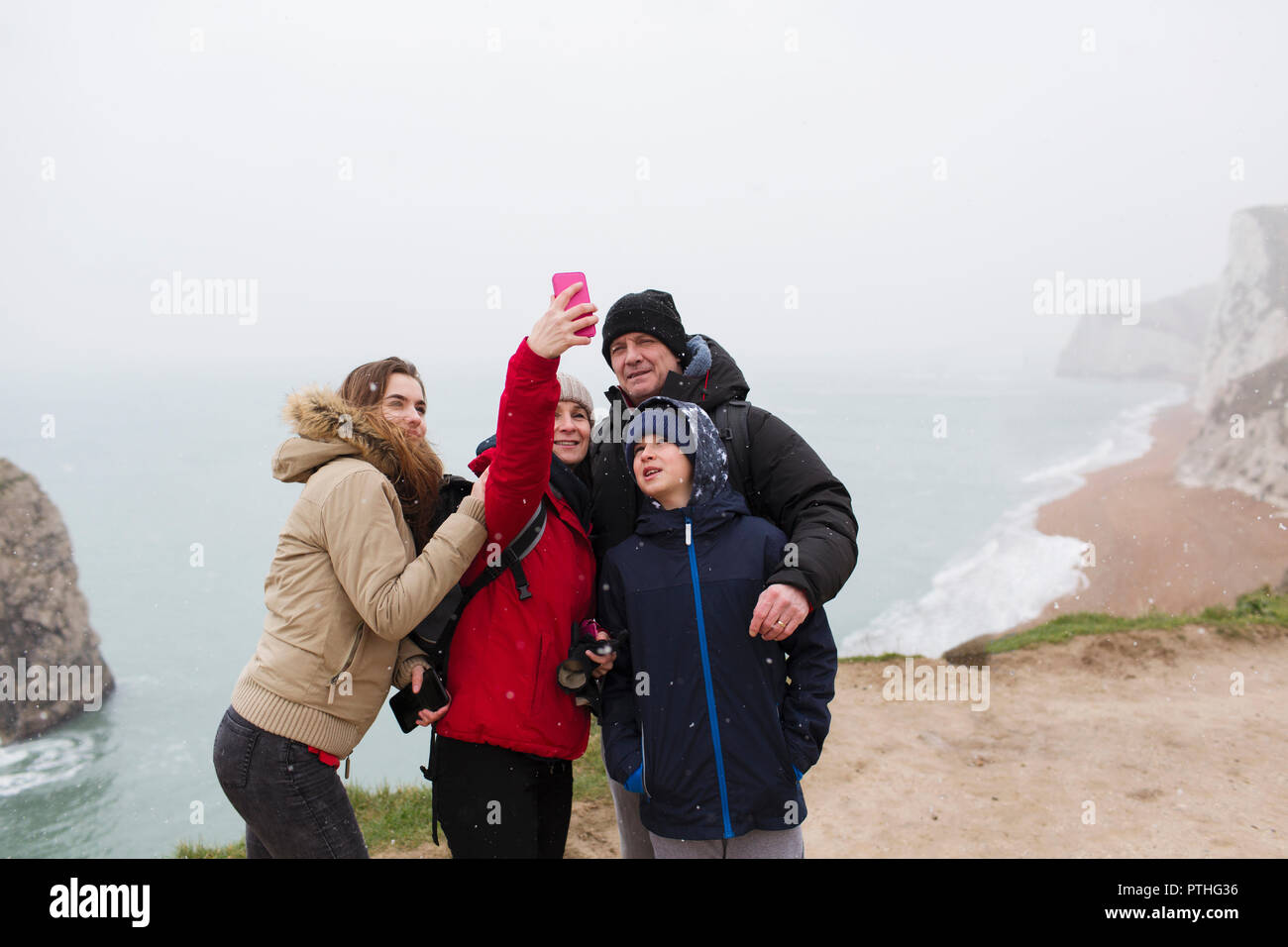 Family with camera phone taking selfie on cliff overlooking ocean Stock Photo
