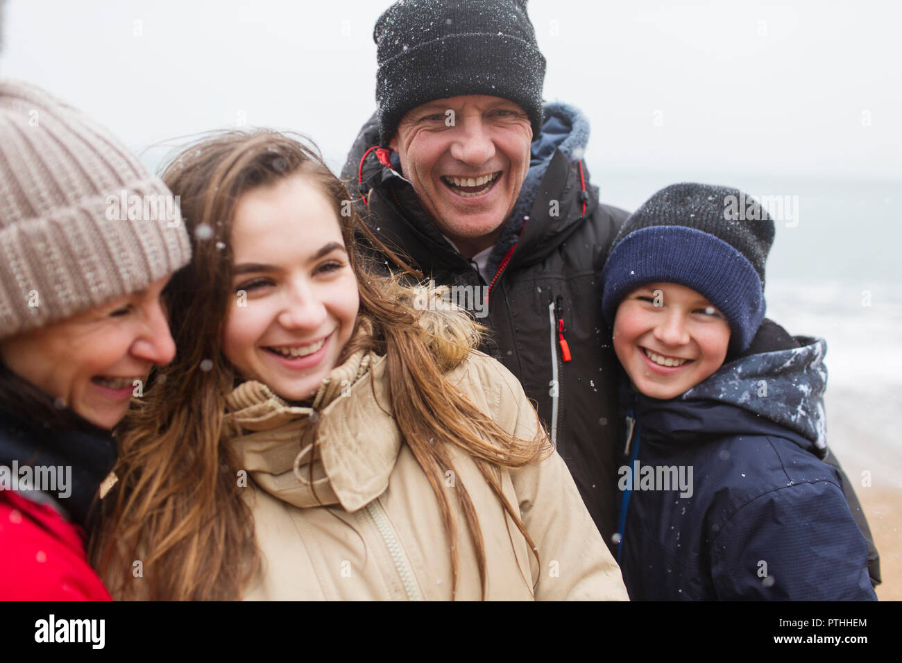 Snow falling over happy family in warm clothing Stock Photo