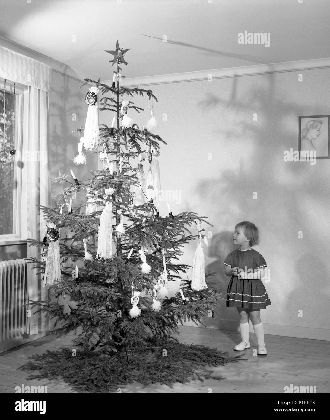 Christmas in the 1950s. A young girl is standing by the christmas tree. Sweden 1950s Ref 3113 Stock Photo