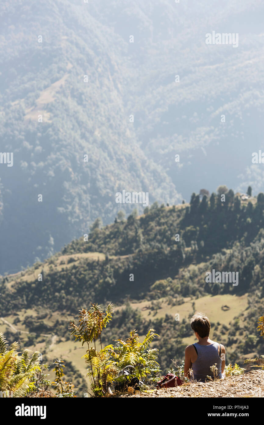 Female hiker resting, enjoying sunny green foothills view, Supi Bageshwar, Uttarakhand, Indian Himalayan Foothills Stock Photo