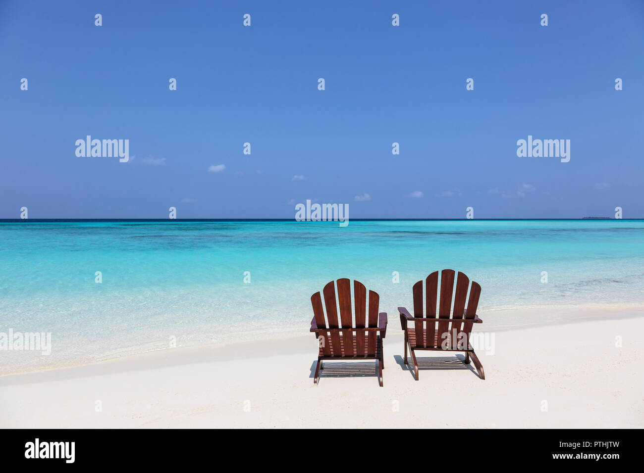 Two Adirondack Chairs On Sunny Tranquil Beach Overlooking Blue