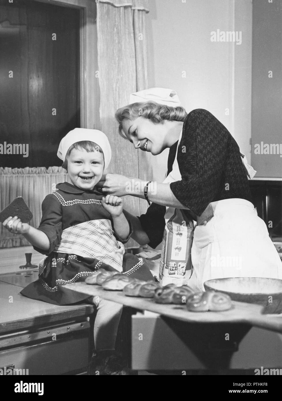 Christmas in the 1950s. Marianne Lestander who is chosen for this years Stockholms Lucia, is baking together with a small girl. Sweden 1959 Stock Photo