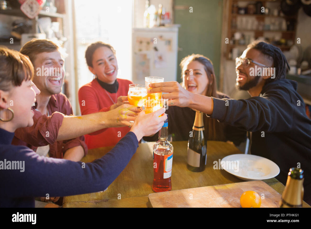 Young adult friends toasting cocktails at apartment kitchen table Stock Photo