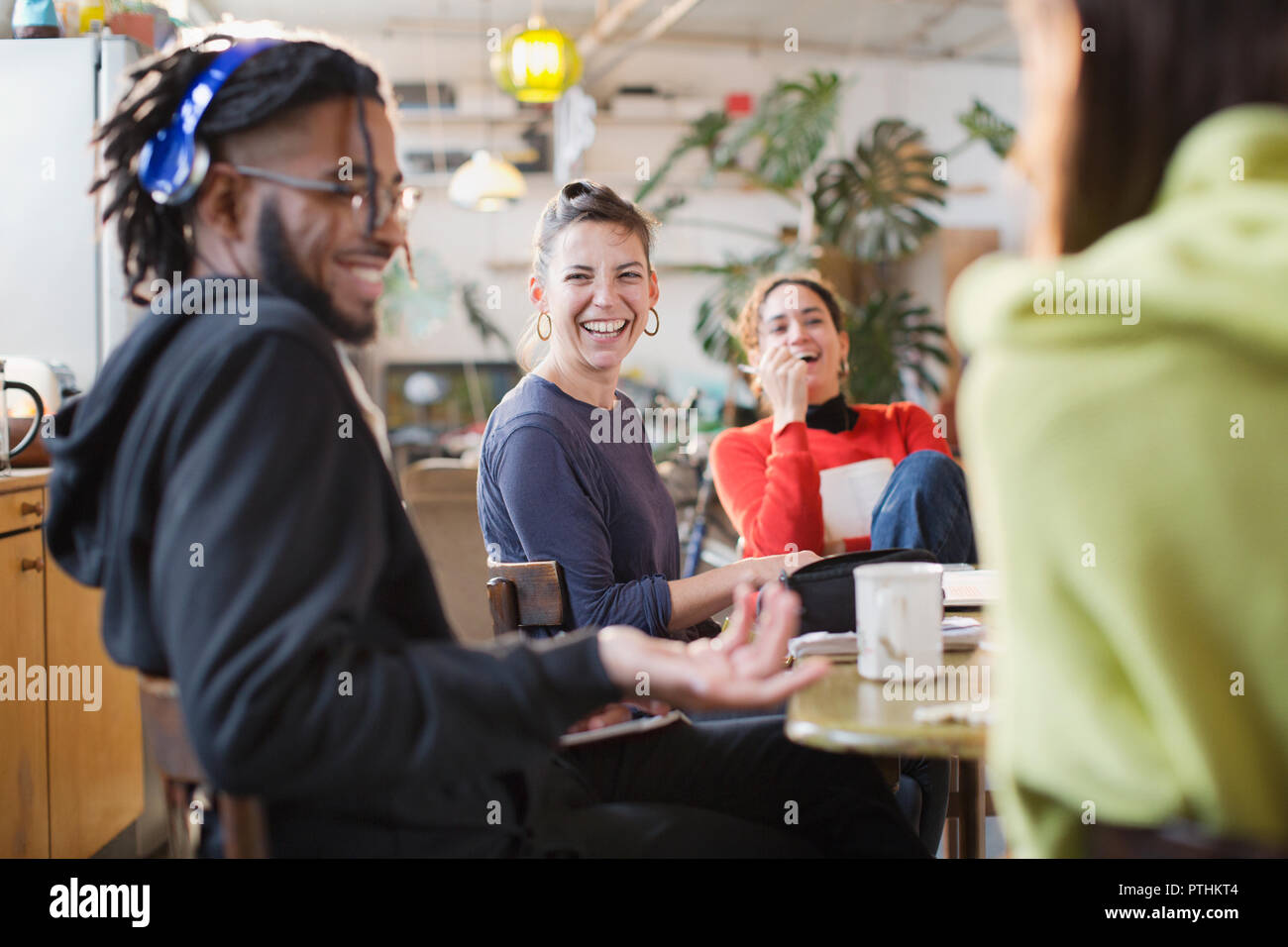 Happy young roommate friends laughing at kitchen table Stock Photo