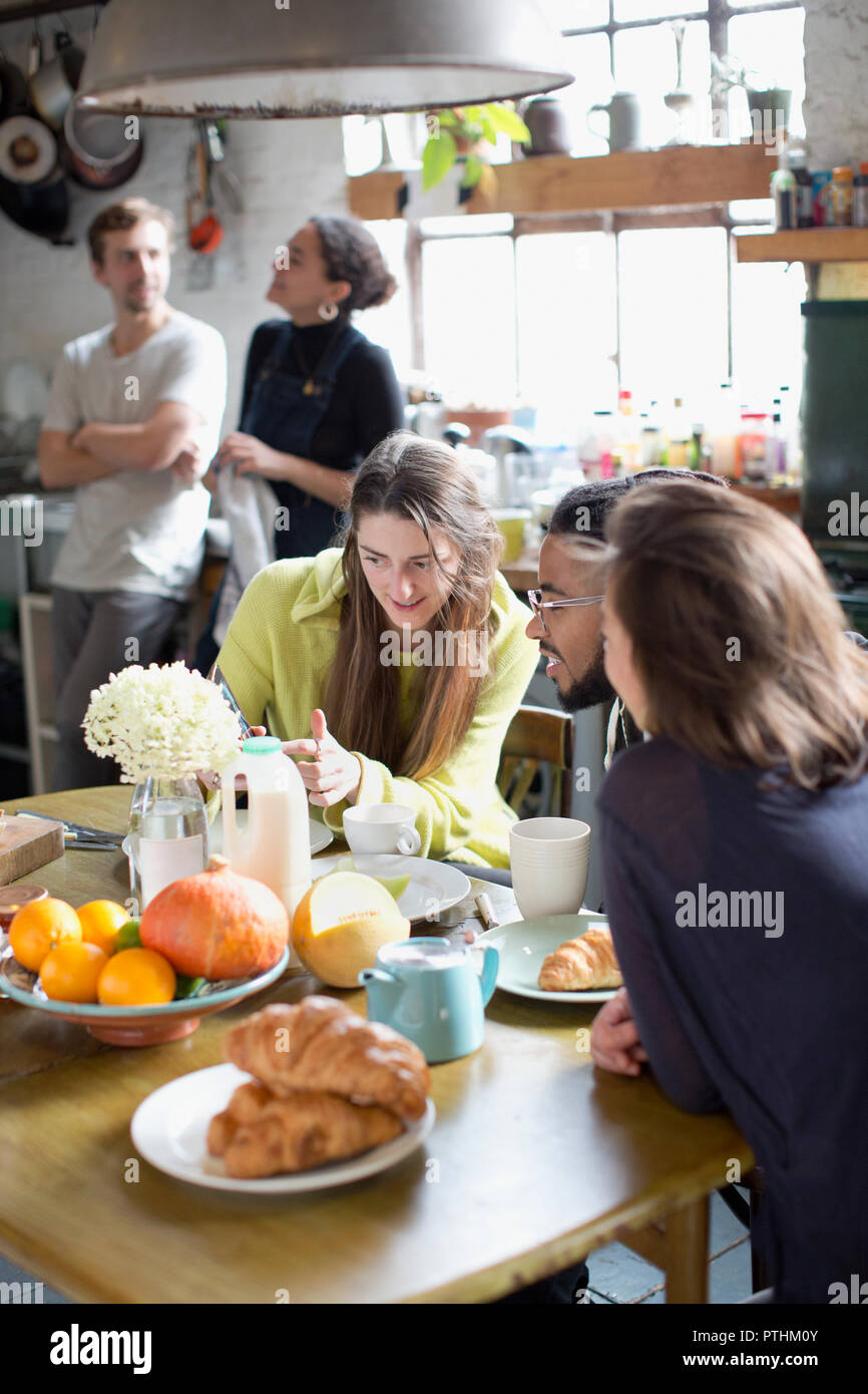 Young college student roommates talking at kitchen table in apartment Stock Photo