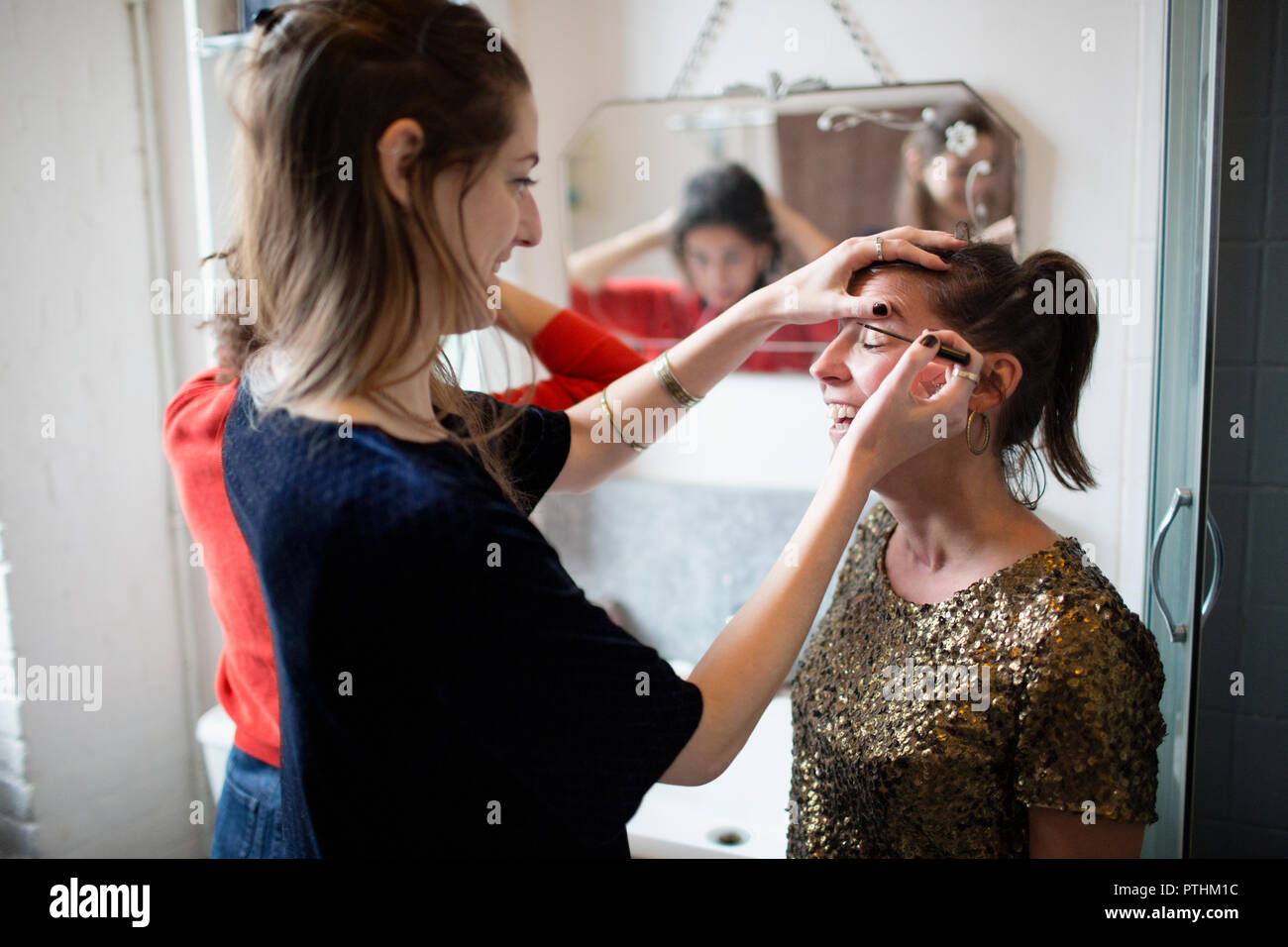 Young women getting ready, applying makeup in bathroom Stock Photo