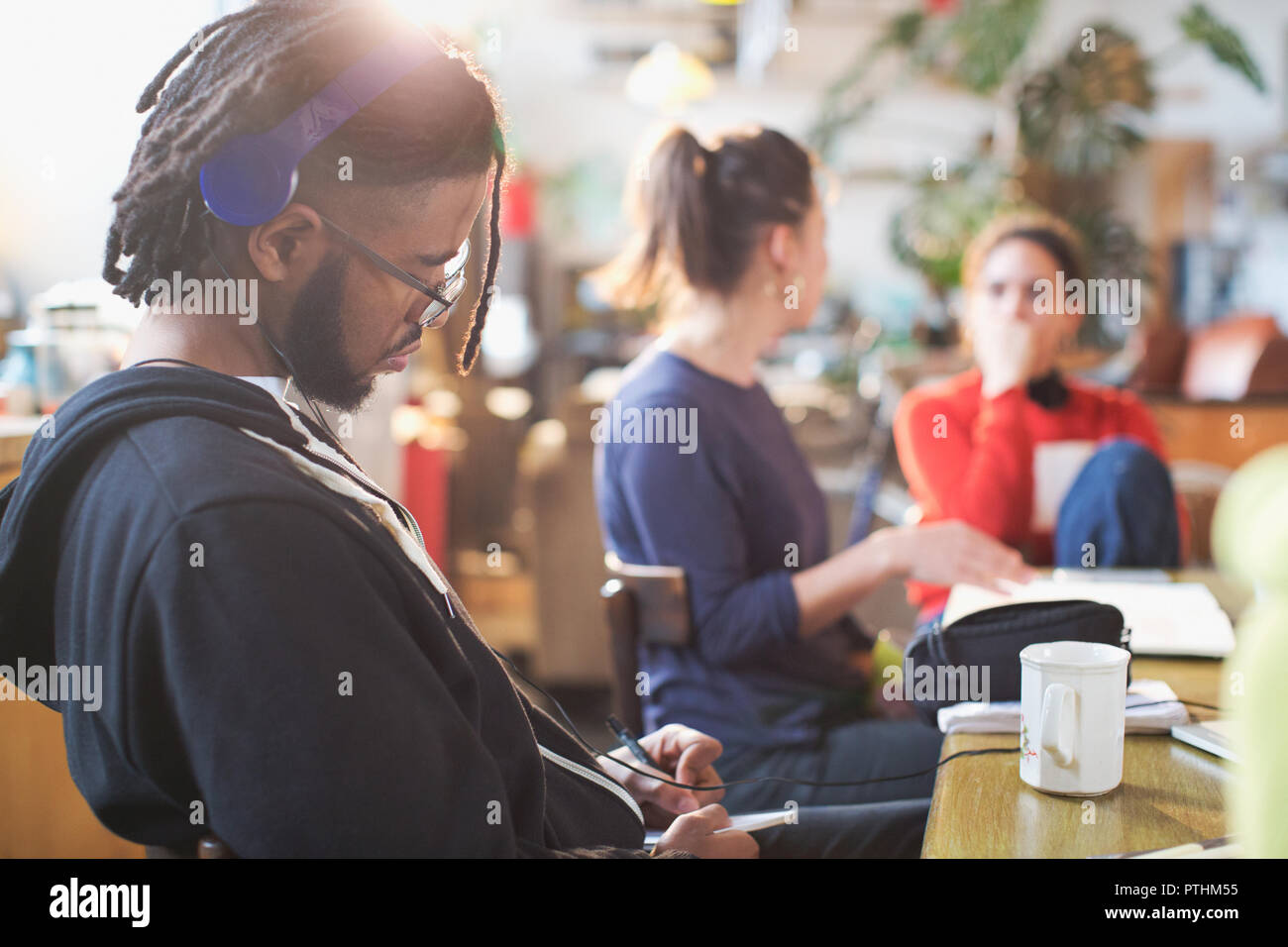 Young man with headphones studying at kitchen table Stock Photo