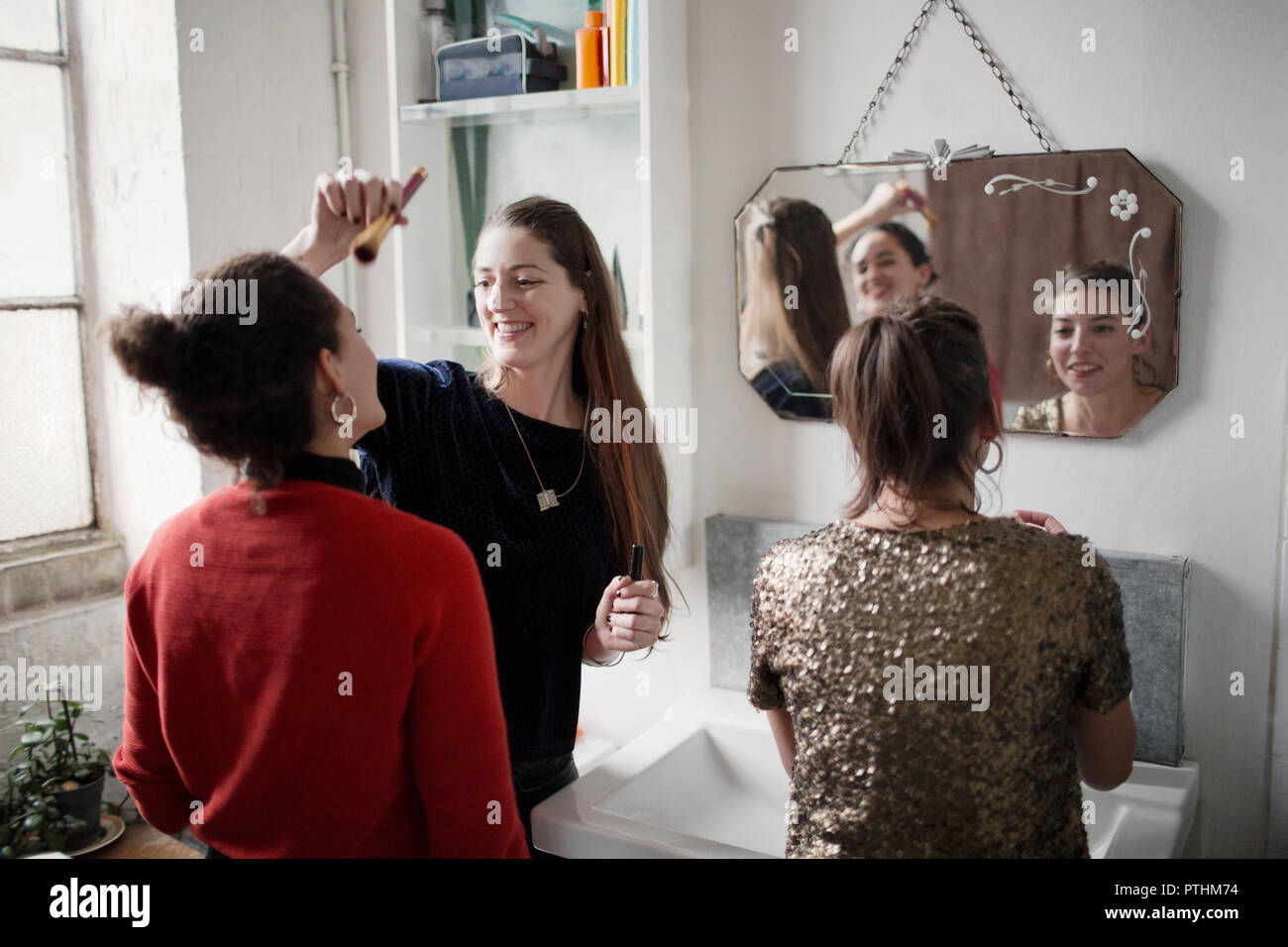 Young women friends getting ready, applying makeup in bathroom Stock Photo