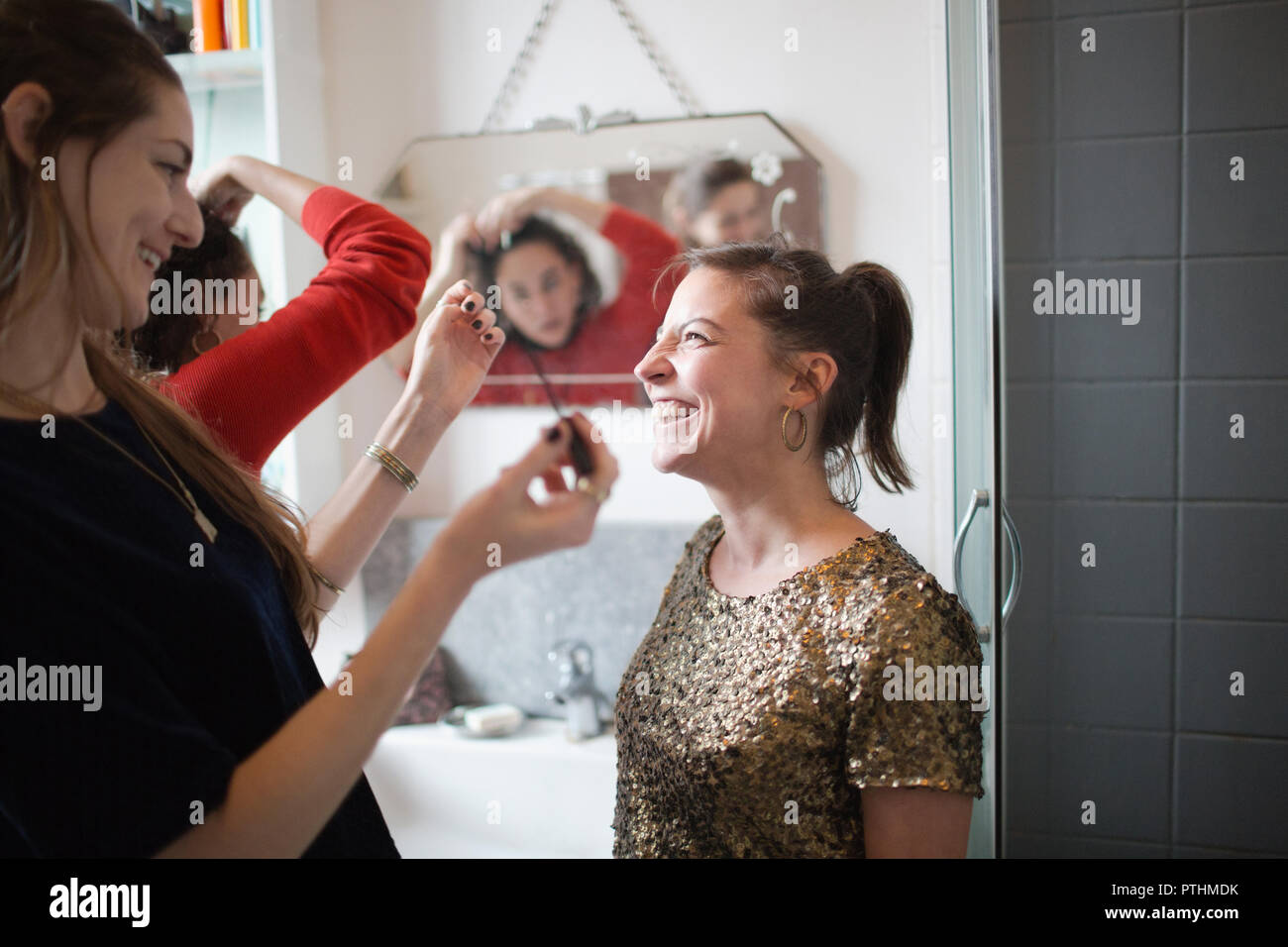 Young women friends getting ready, putting on makeup in bathroom Stock Photo