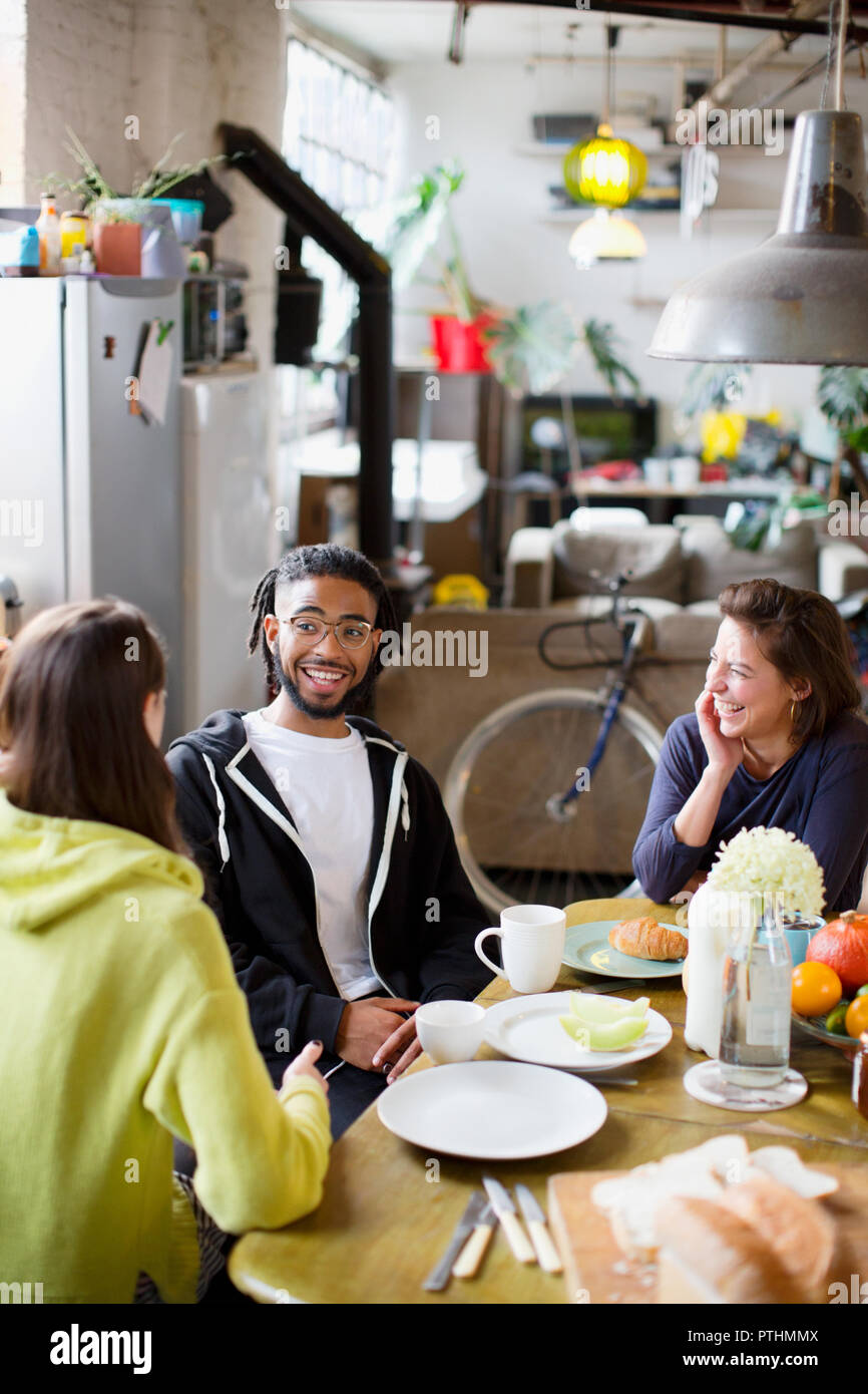 Young adult roommate friends talking at breakfast table in apartment Stock Photo