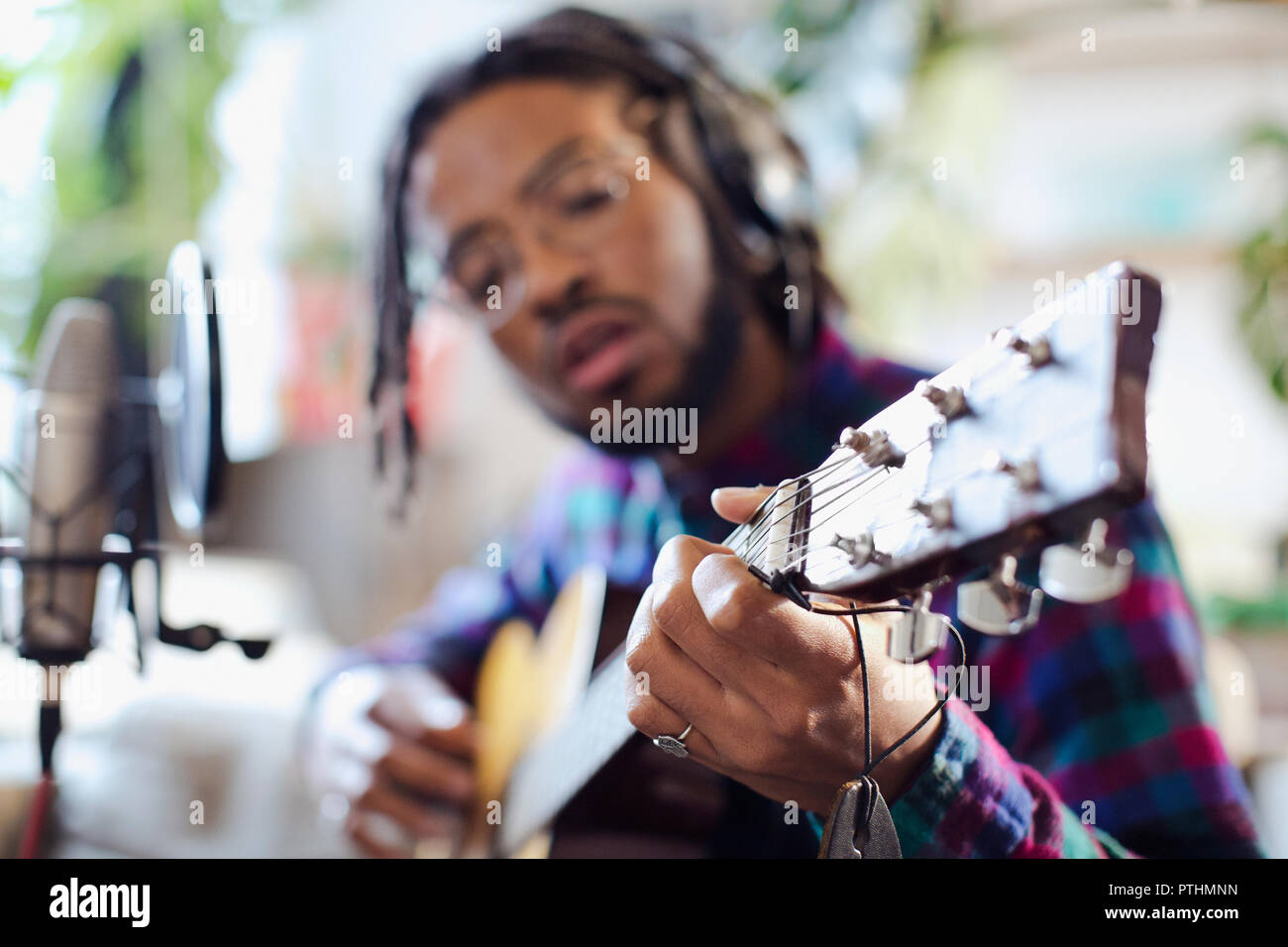 Young male musician recording music, playing guitar at microphone Stock Photo