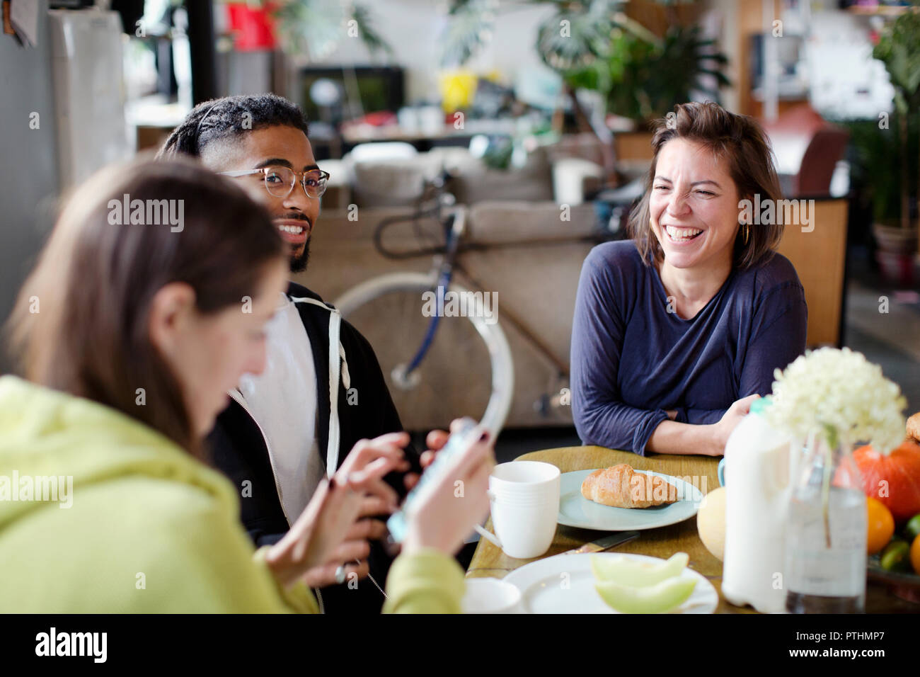 Young adult roommate friends enjoying breakfast at apartment kitchen table Stock Photo