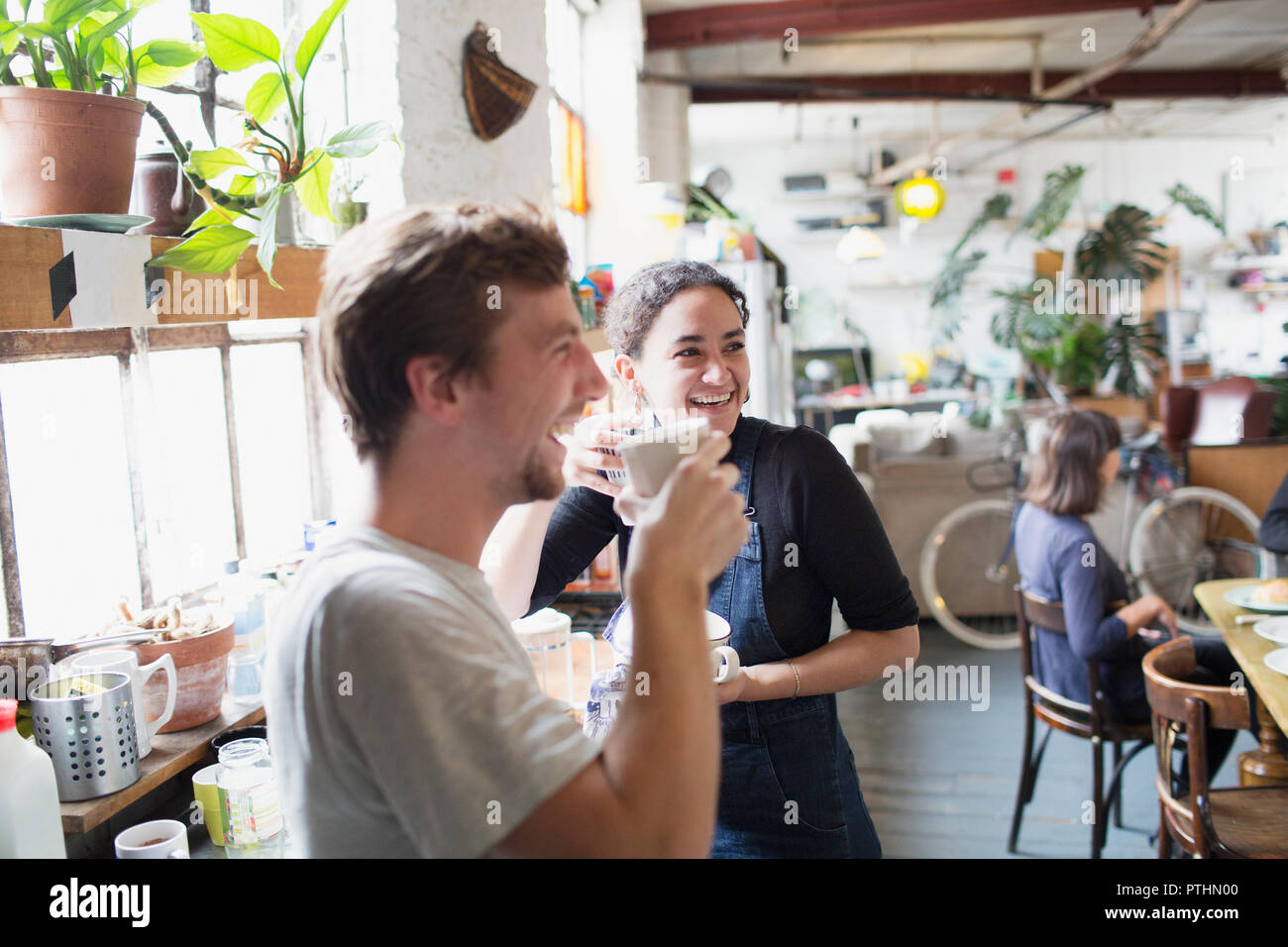 Happy roommates enjoying coffee in apartment kitchen Stock Photo