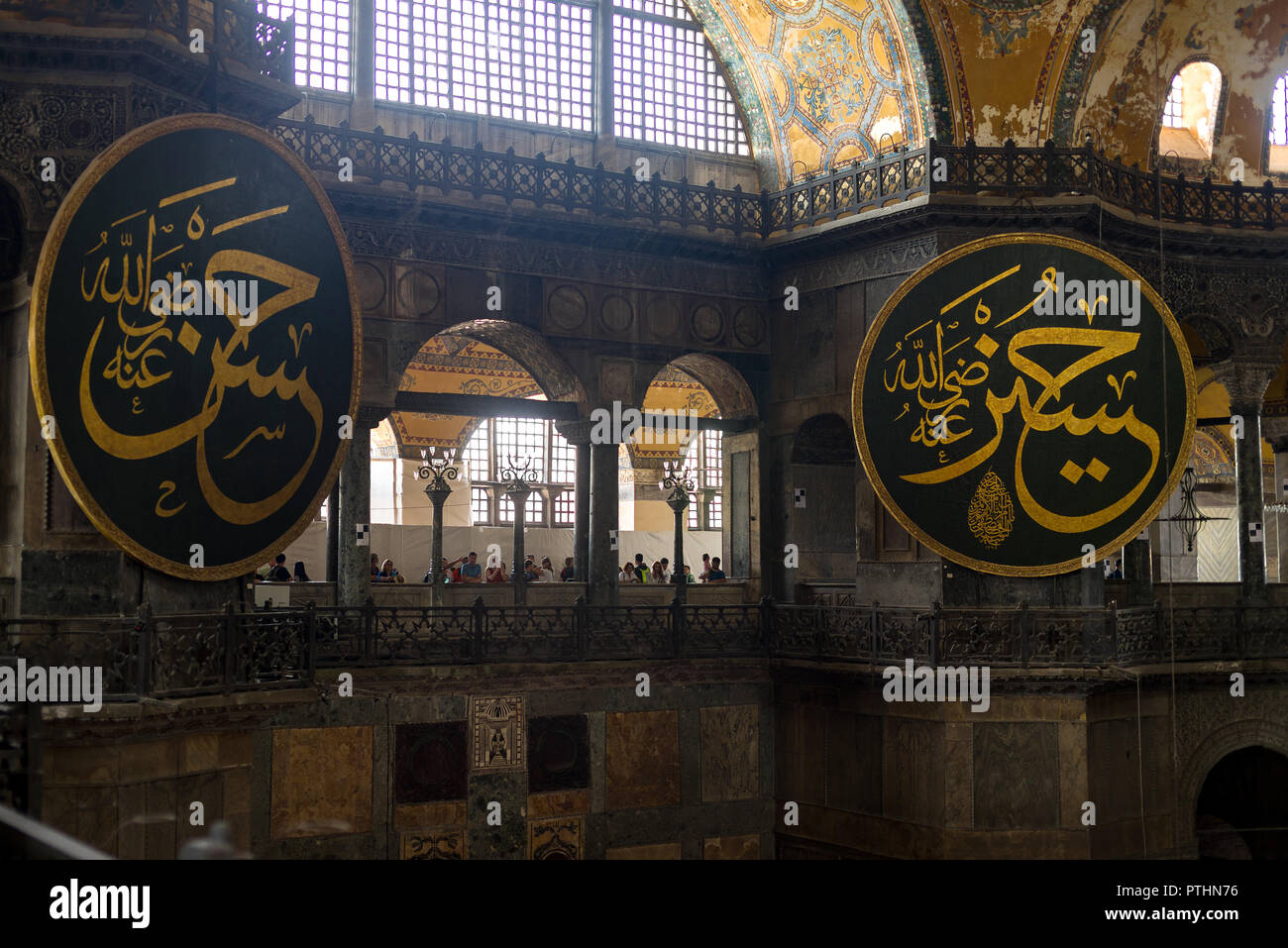 View of the 1st floor large calligraphic roundel panes with tourists at one of the balconies, Hagia Sophia museum, Istanbul, Turkey Stock Photo