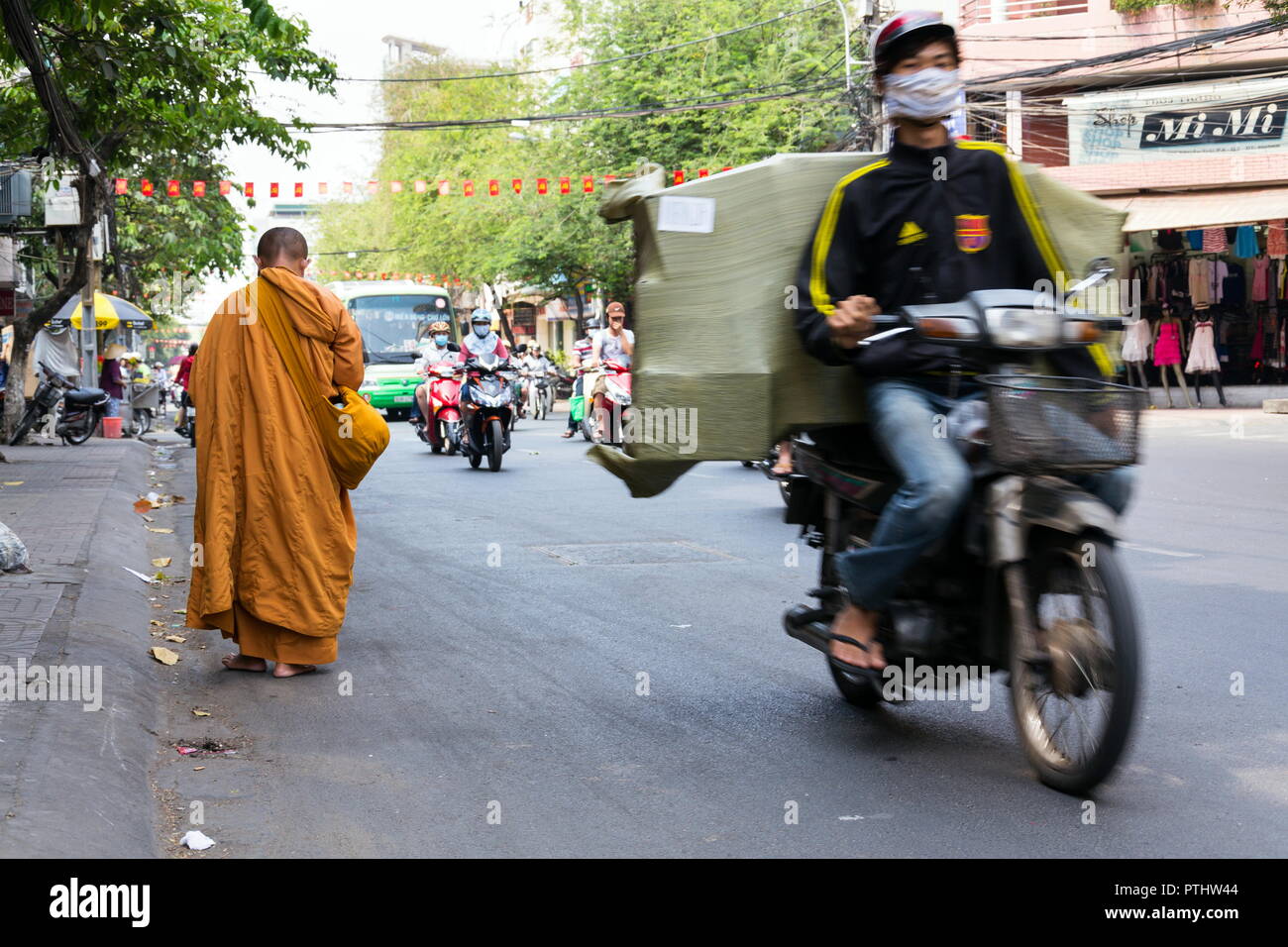 HO CHI MINH CITY - FEBRUARY 5: Monk walks barefoot on busy street on February 5, 2012 in Ho Chi Minh City, Vietnam. Stock Photo