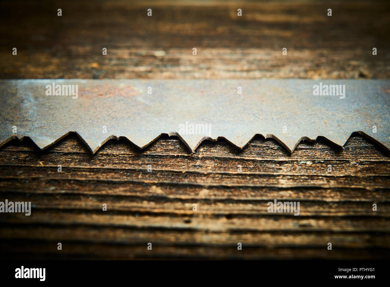 Close up of an old and rusty antique handsaw om wooden desk. Selective focus Stock Photo