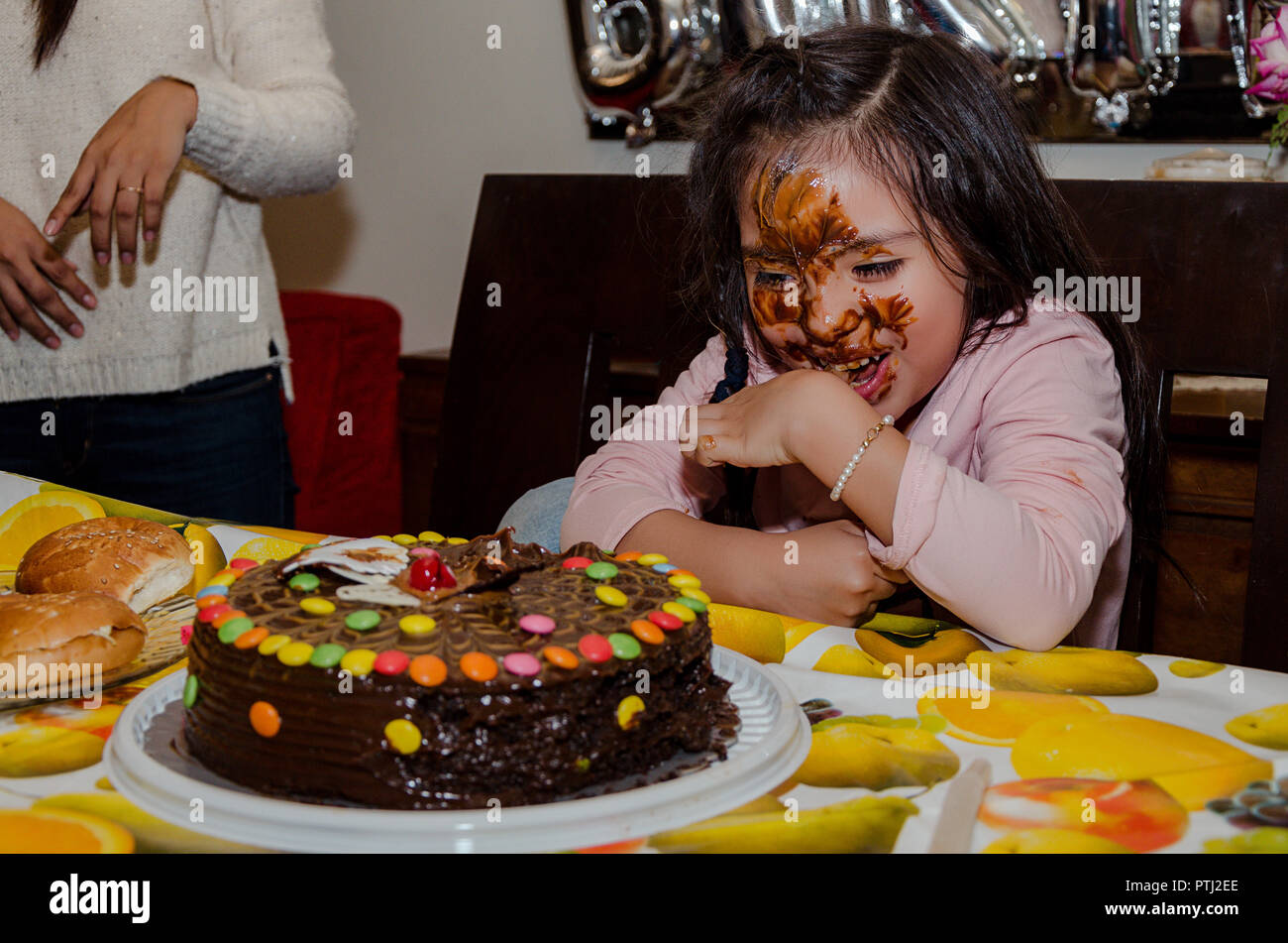 6 year old girl celebrating her birthday by putting her face inside the chocolate cake Stock Photo