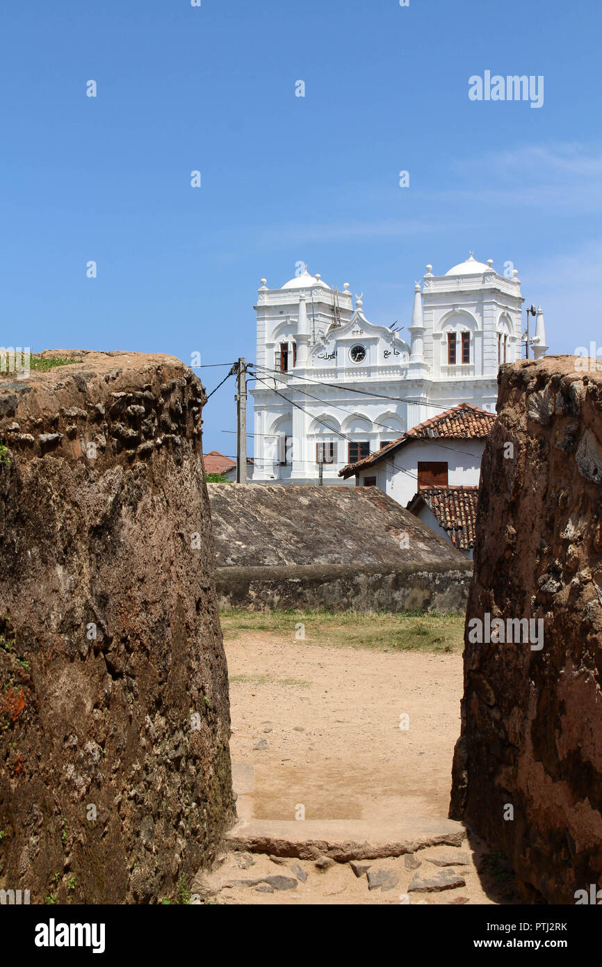 The Meera Mosqe within the Galle Fort, seen from between of two rocks. Taken in Sri Lanka, August 2018. Stock Photo