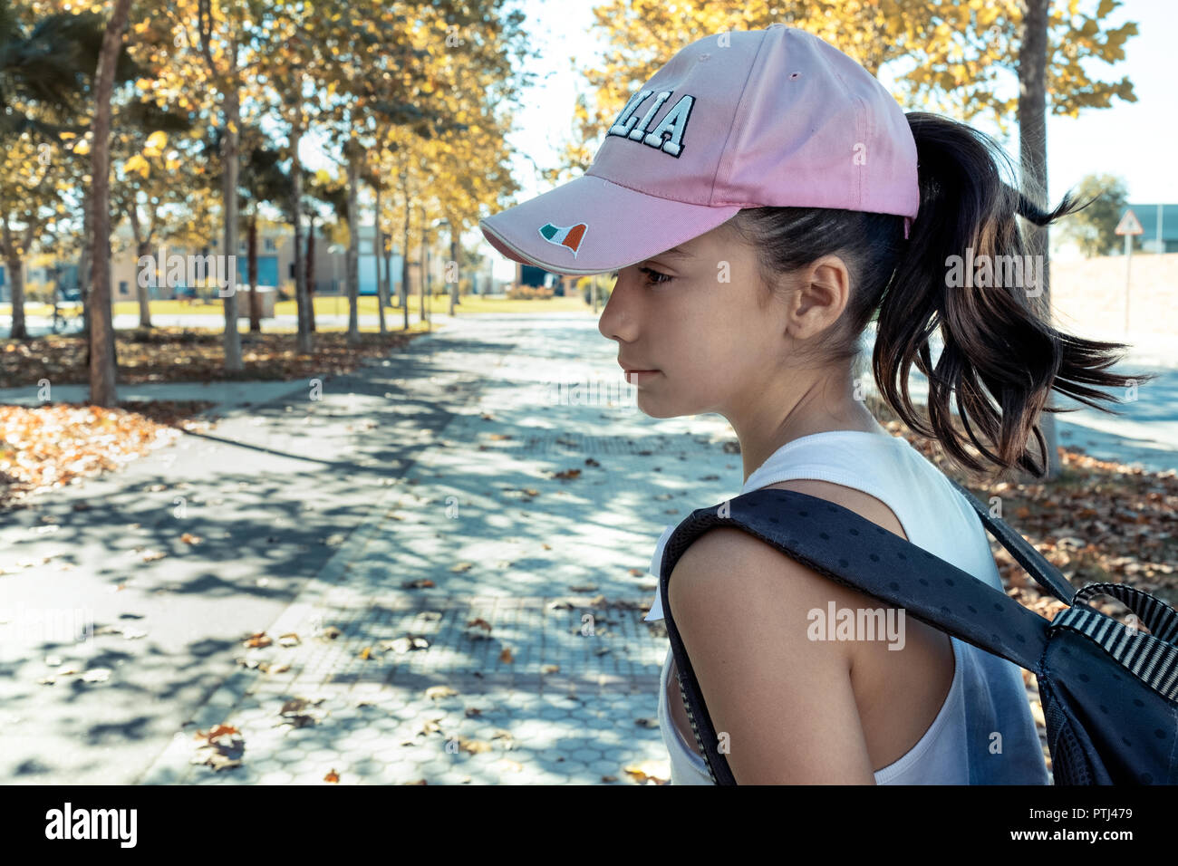 little girl with pink cap and backpack in the park Stock Photo