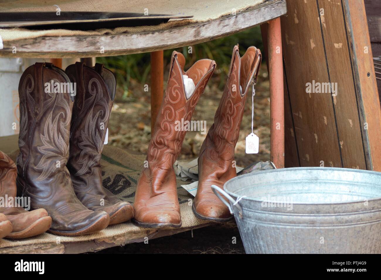 Old used and slightly worn cowboy boots for sale at a local yard sale. Stock Photo