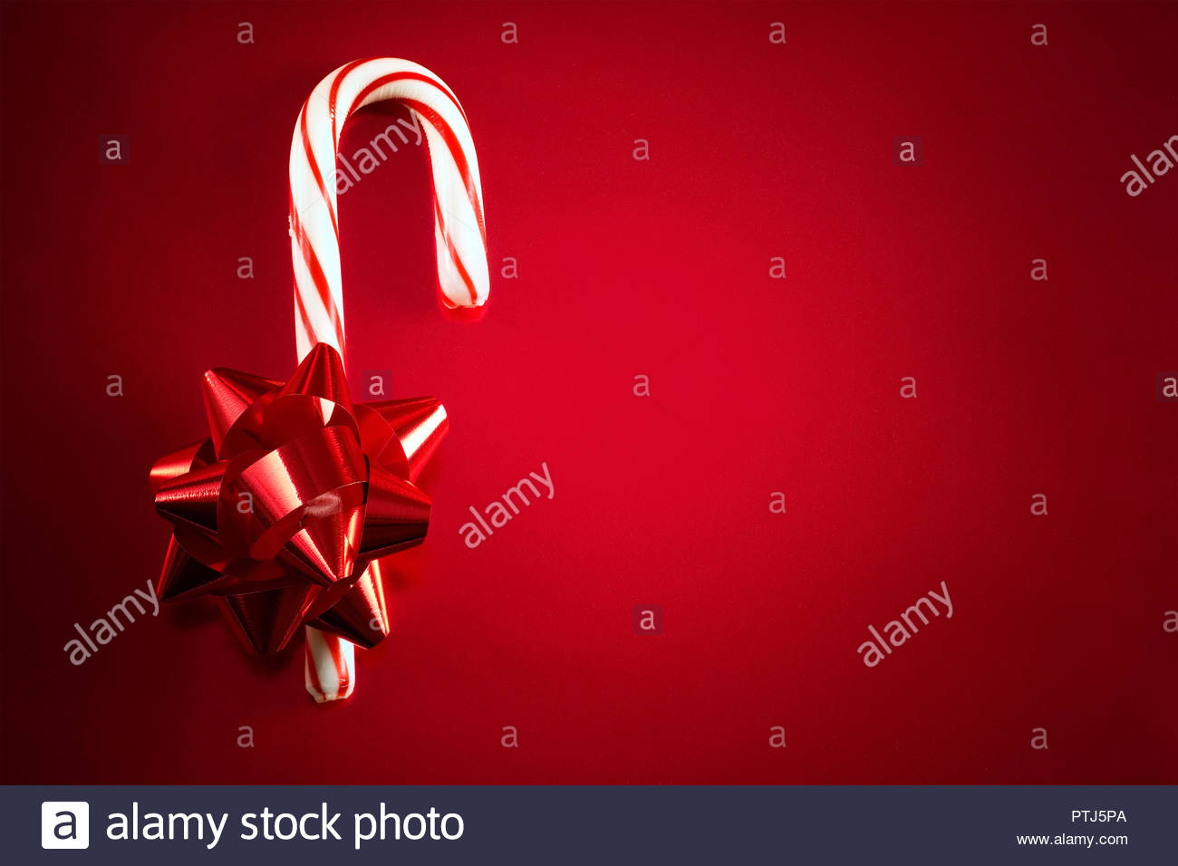 red foil bow and candy cane on red background for christmas themed