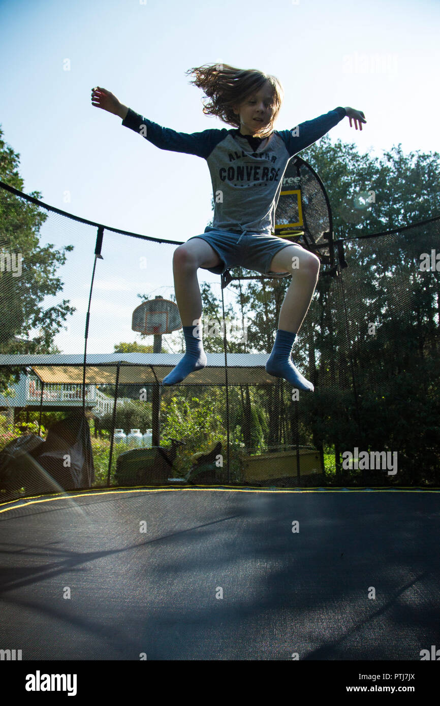 boy jumping with frog legs on a trampoline Stock Photo